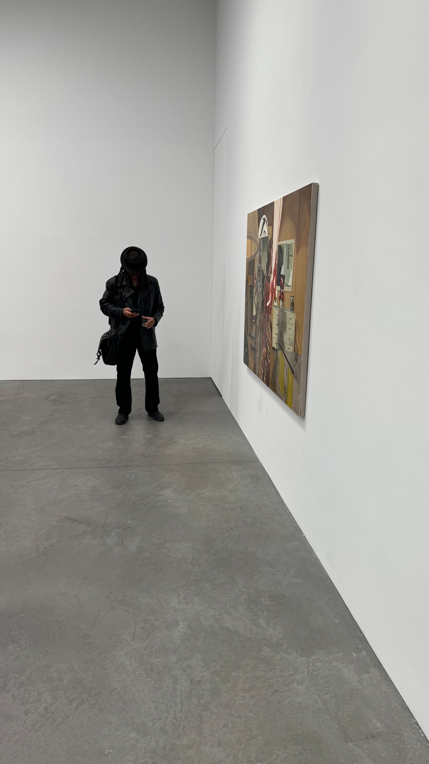 Minimalist art gallery space with white walls and concrete floor showing framed artwork. New York.