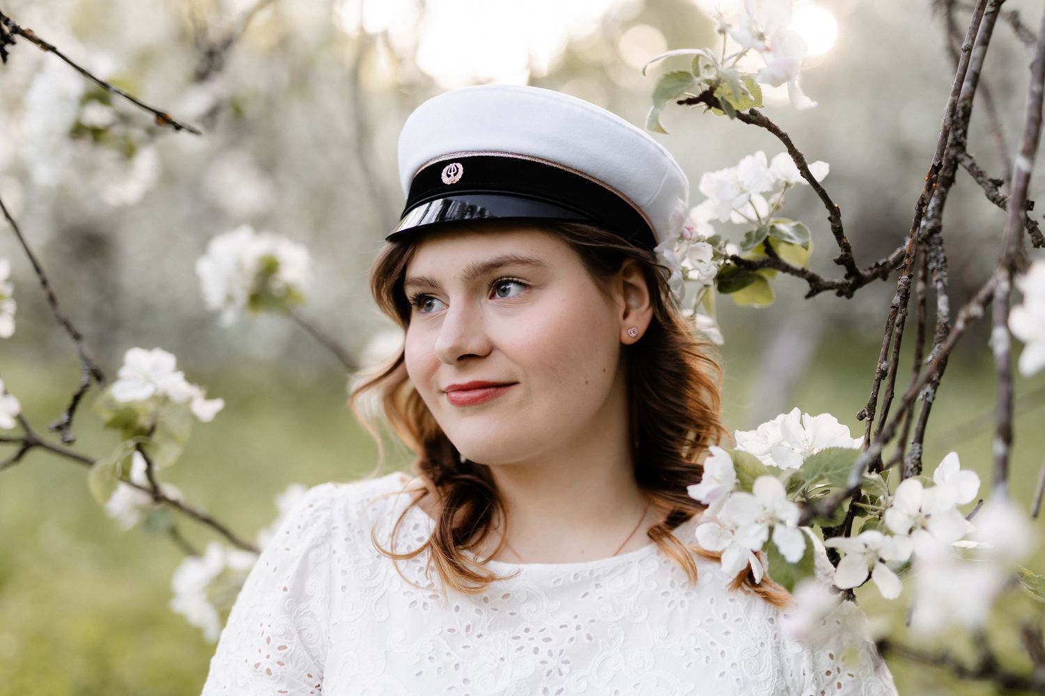 Ylioppilas omenatarhassa omenankukkien ympäröimänä.