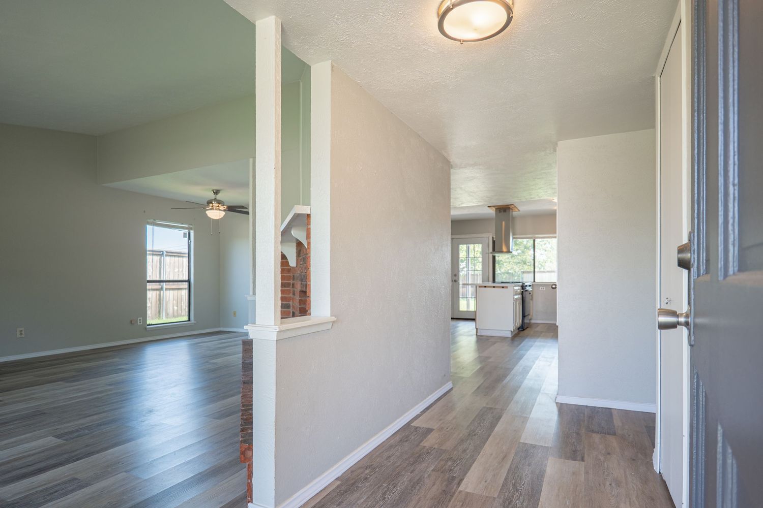 Long hallway features grey laminate flooring, white walls, recessed lighting and small windows near the ceiling for natural light.