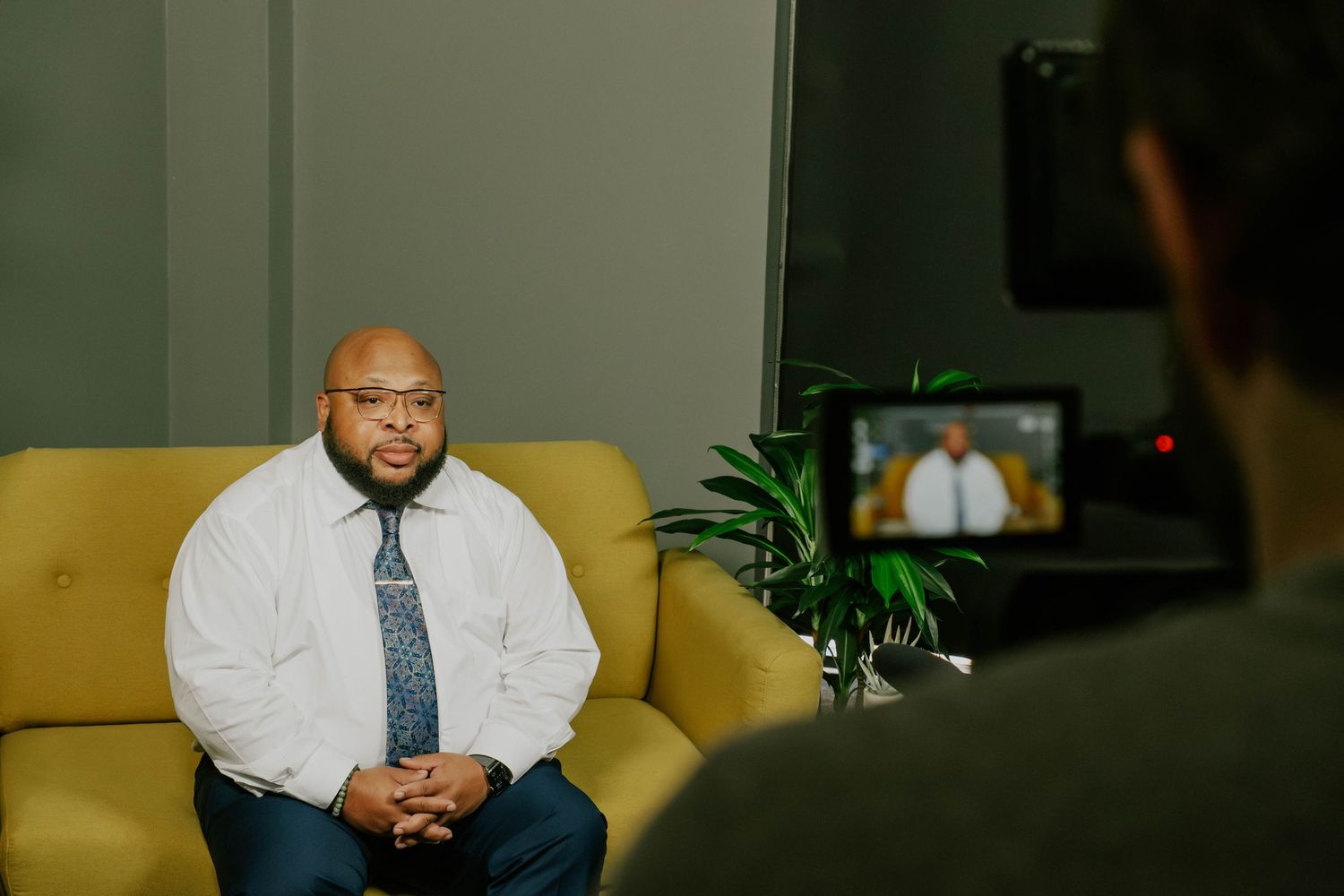 Professional portrait session in a dimly lit room with green walls and yellow couch.
