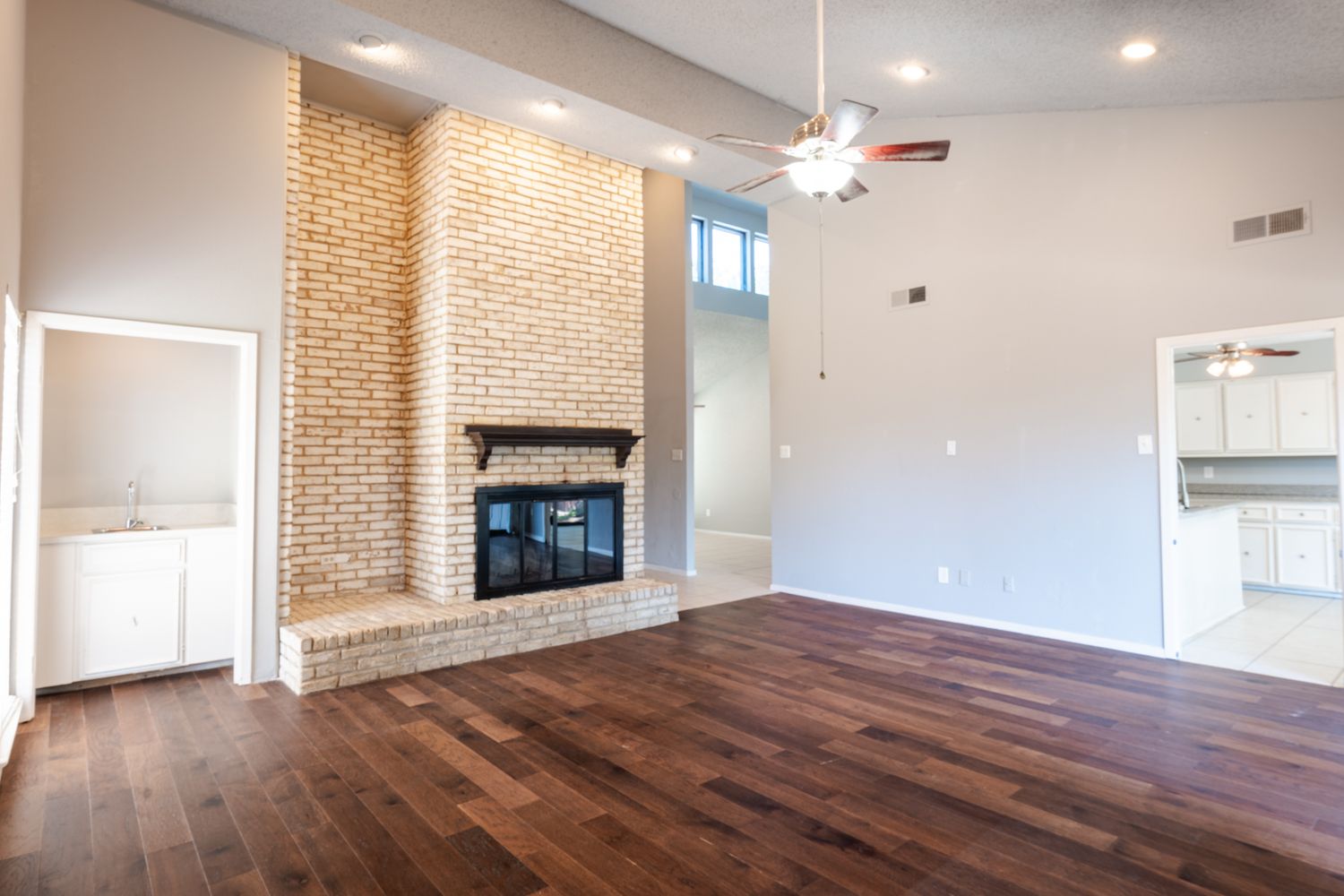 Modern open concept living room with exposed brick walls, hardwood floors, and recessed lighting.