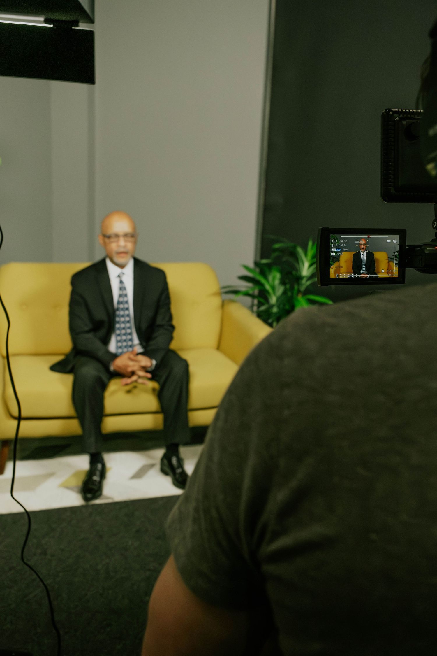 Interview setup in a modern office lounge with yellow couch and indoor plants.