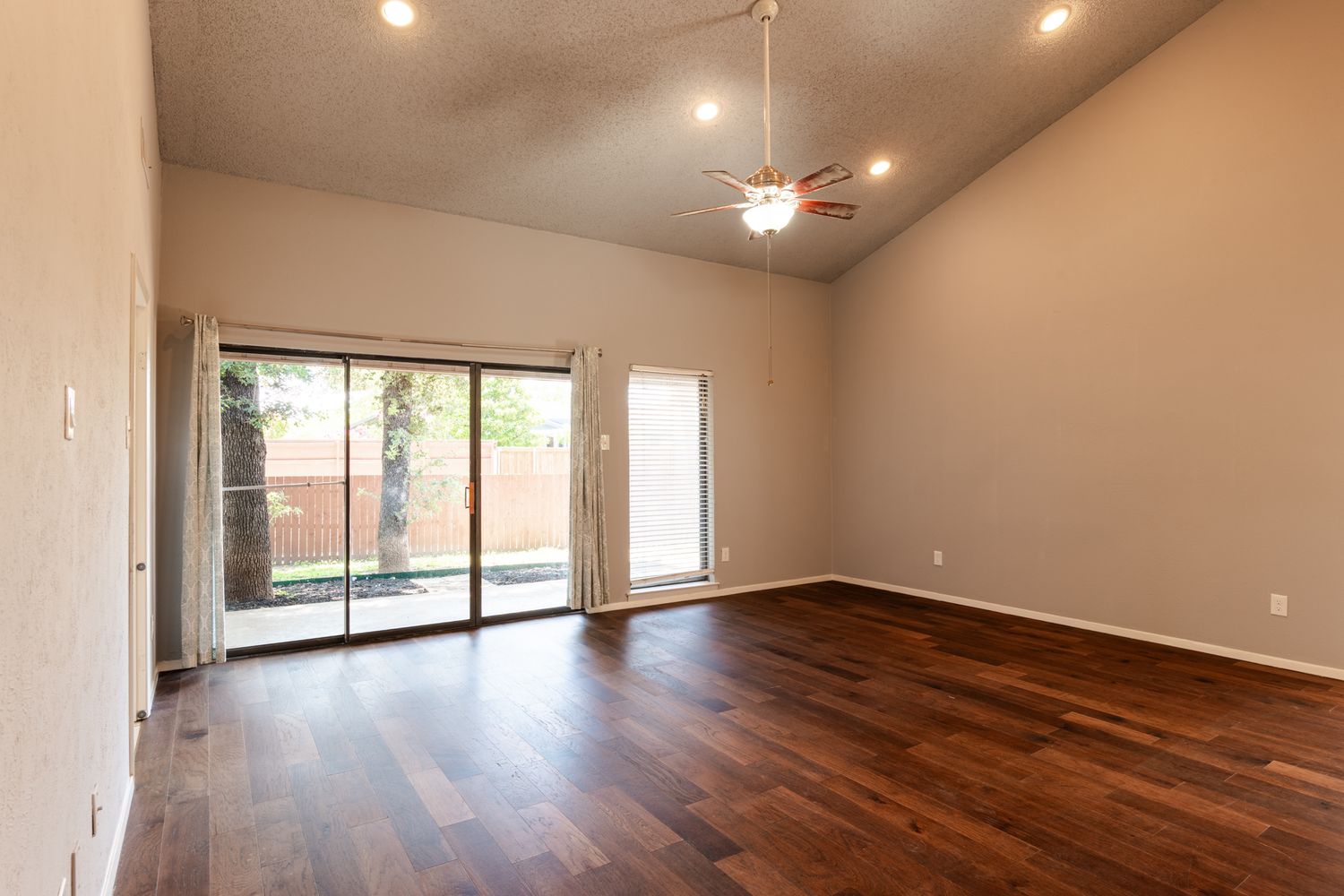 Bright living space features modern ceiling fan, recessed lighting, and polished wood floors.