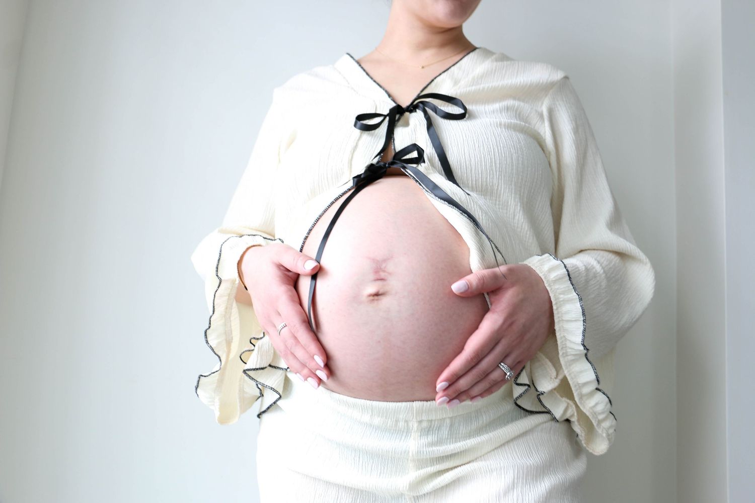 Maternity photo showing pregnant belly in white ruffled top.