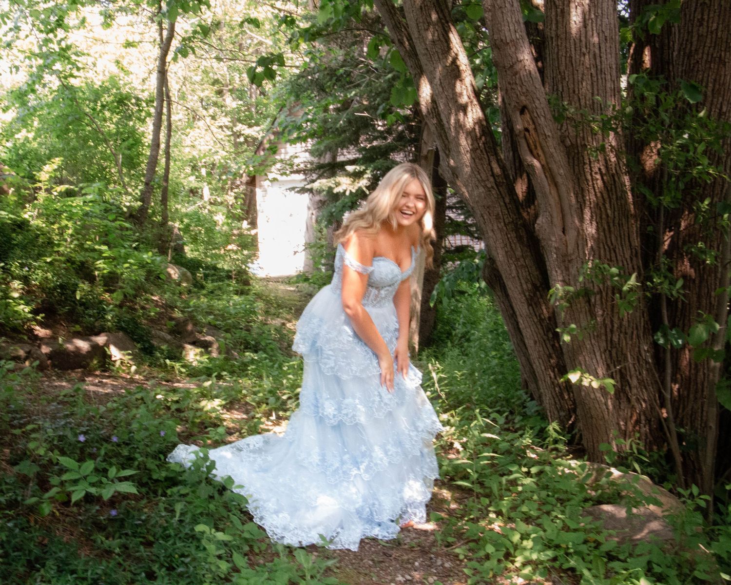 A romantic scene in a forest pathway with someone wearing a flowing light blue dress and long hair.
