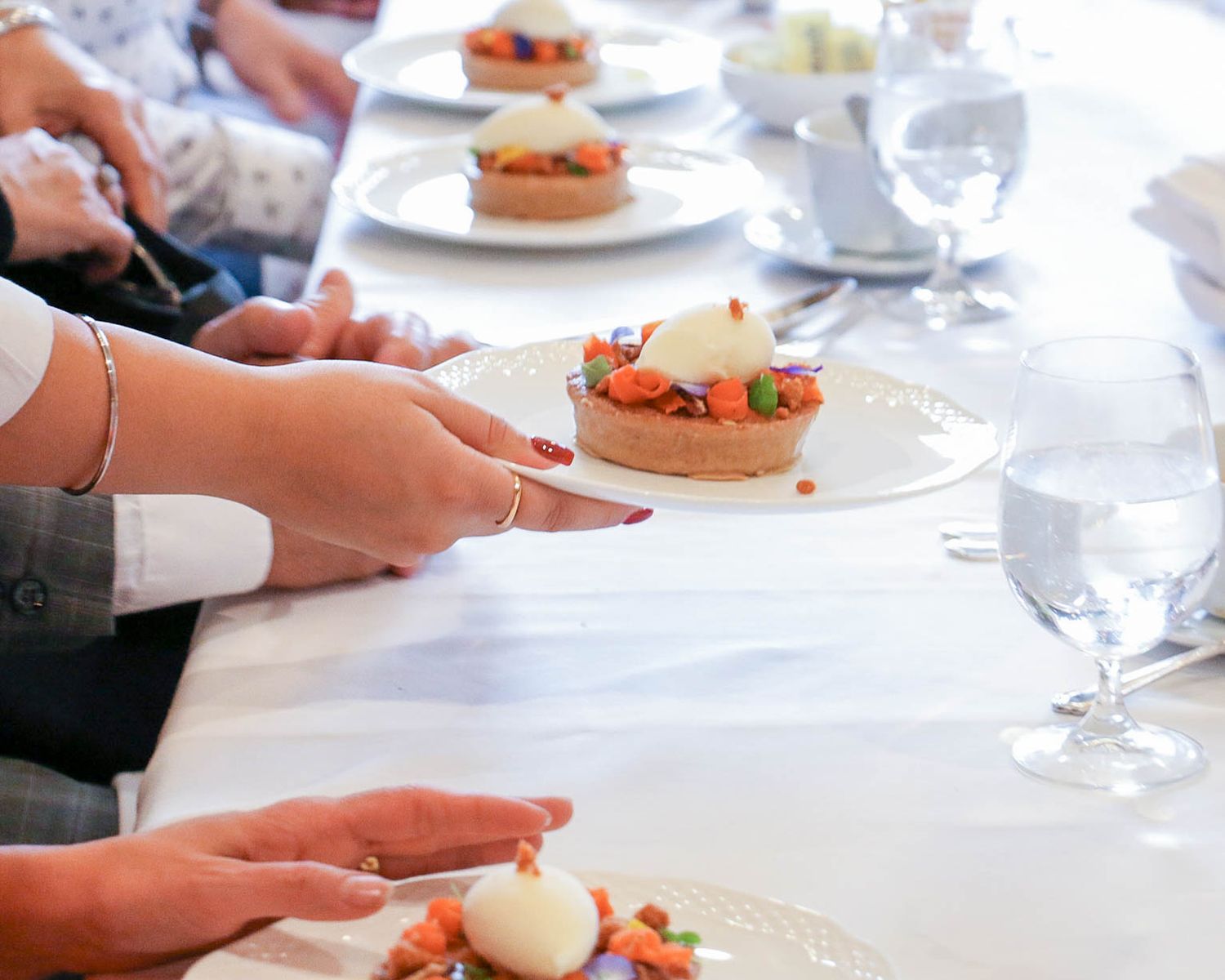Elegant place settings with plated appetizers at a formal dining event.