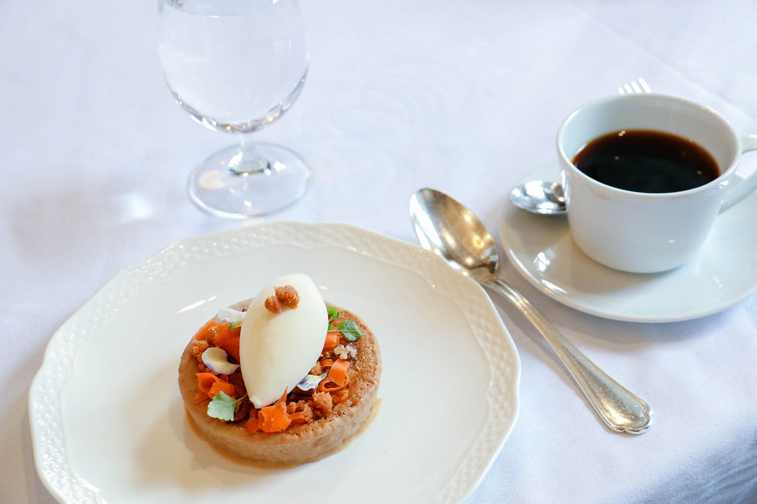Elegant plated appetizer with poached egg served alongside coffee on white china.