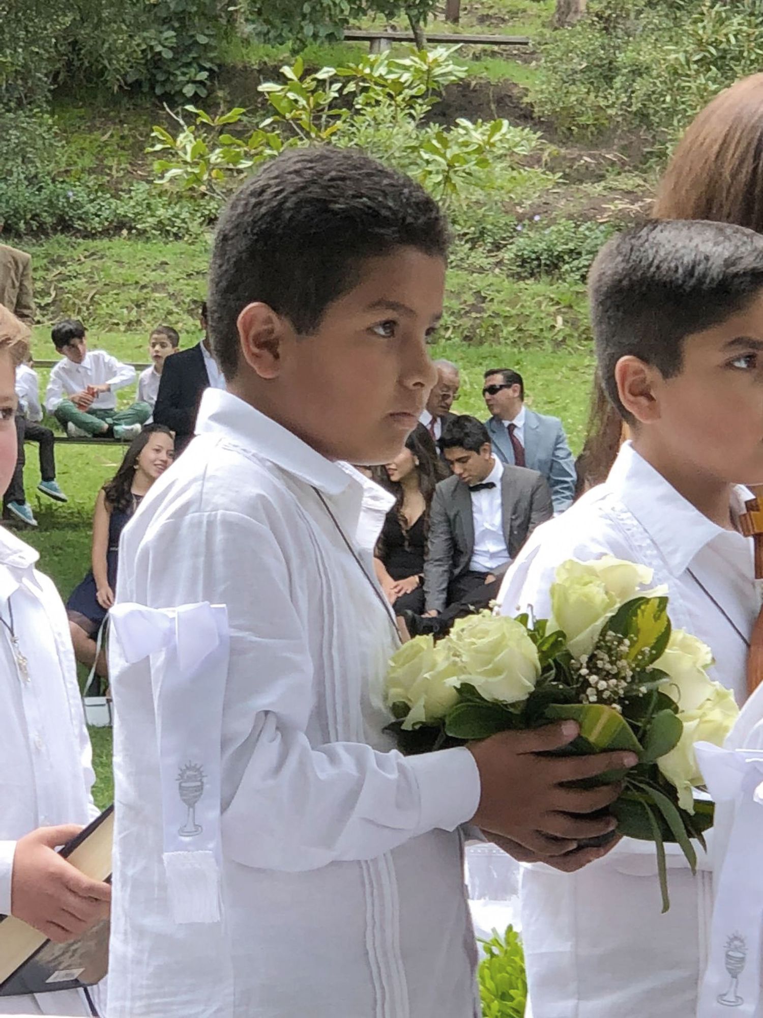 Young boy presenting a bouquet of flowers to the Virgin Mary during his First Communion celebration.