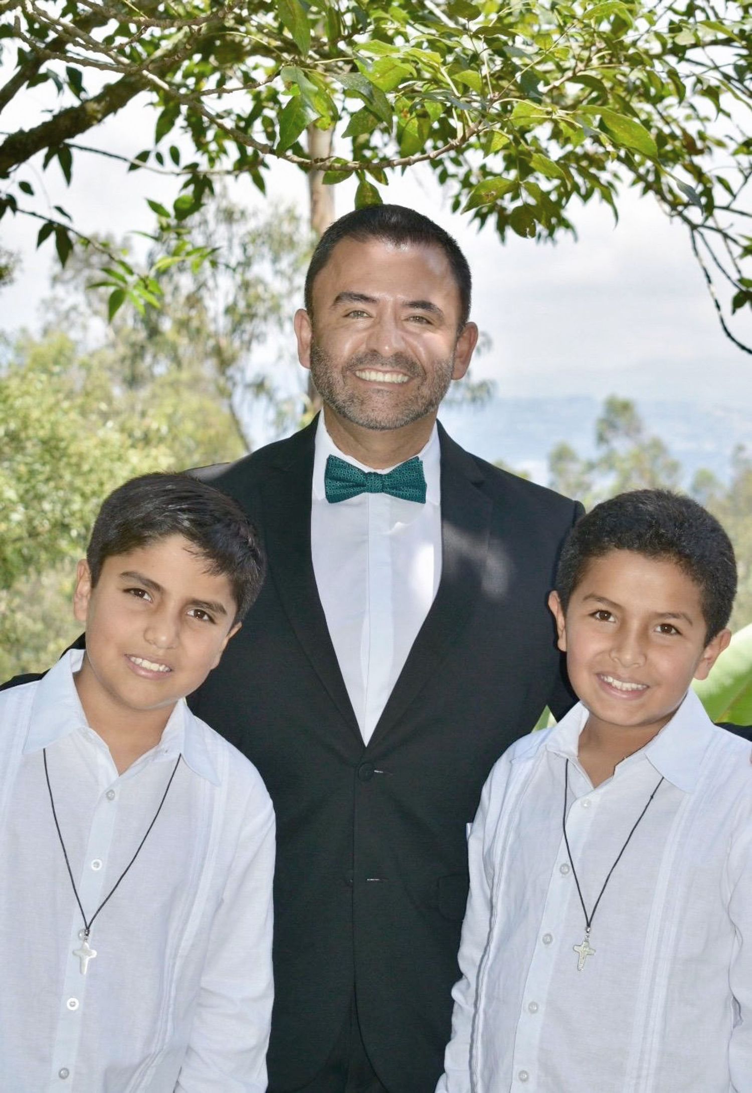 First Communion moment with two children standing beside their proud godfather after the ceremony.