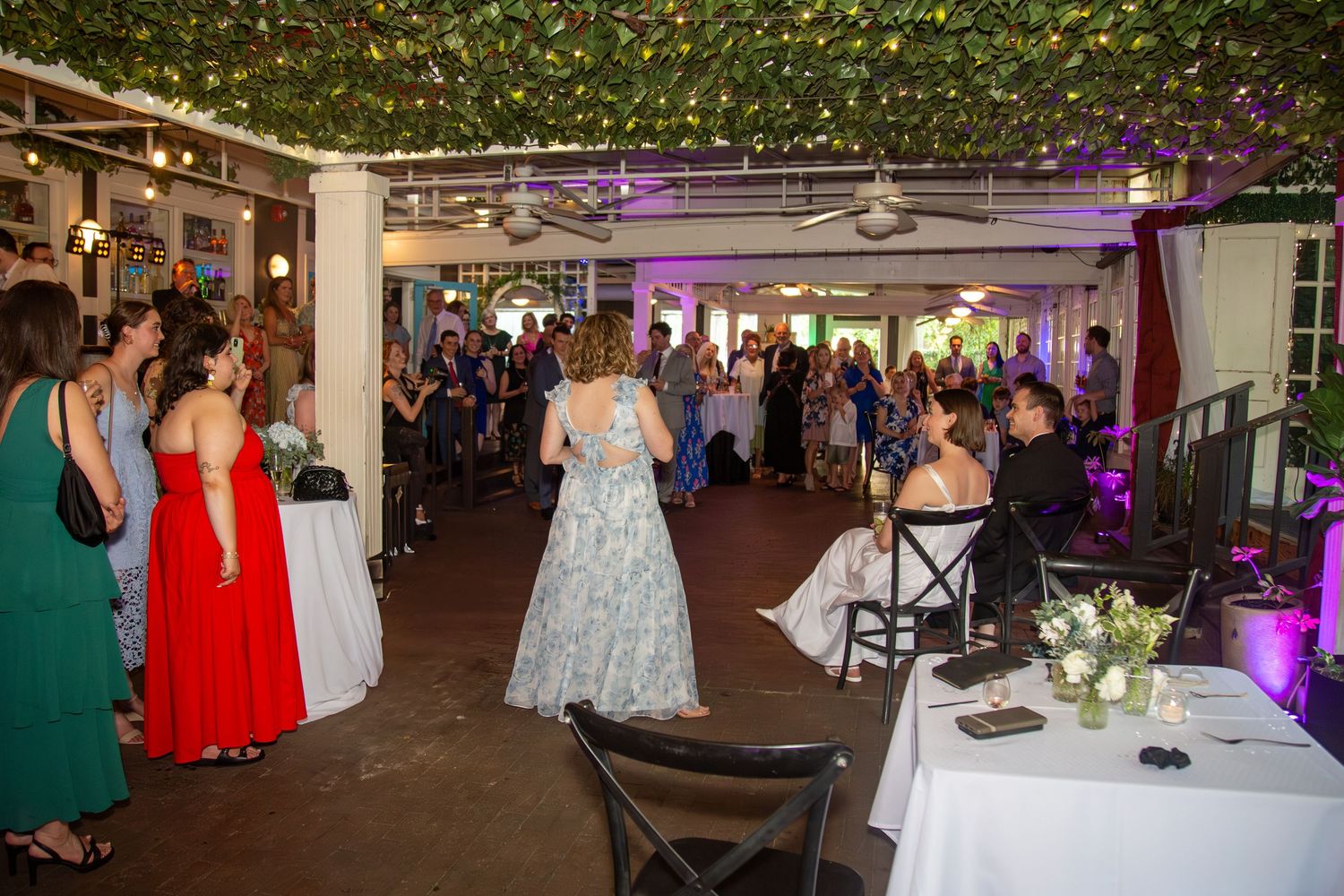 Full reception crowd focused on the newlyweds giving a heartfelt speech.