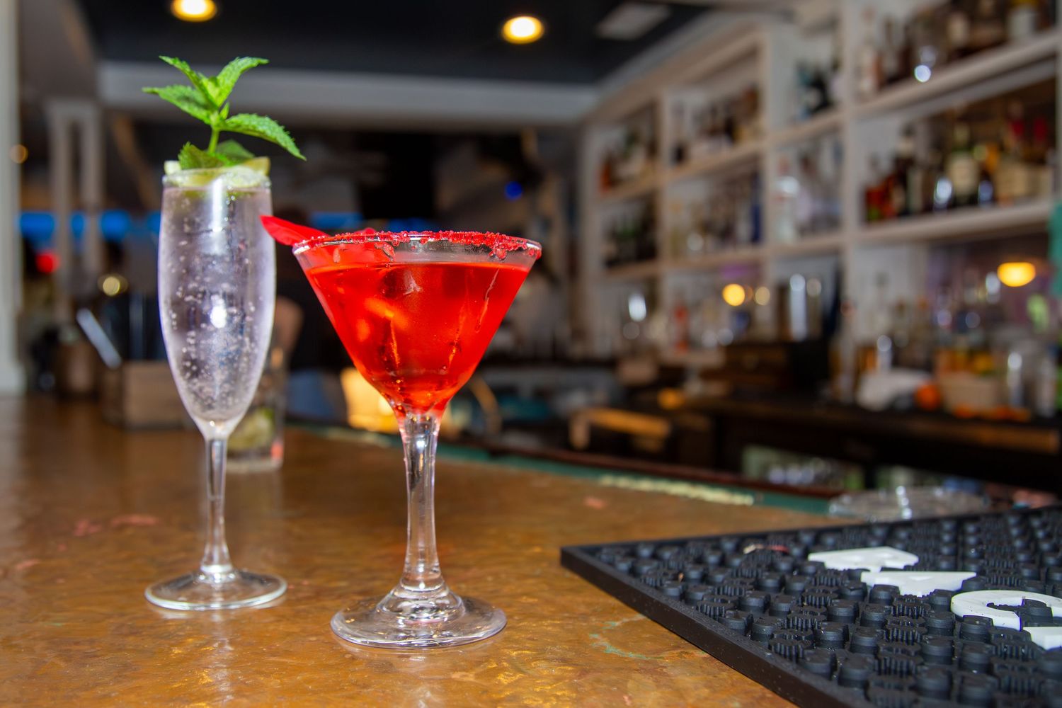 Two artisan cocktails set on a polished bar ready to be served.