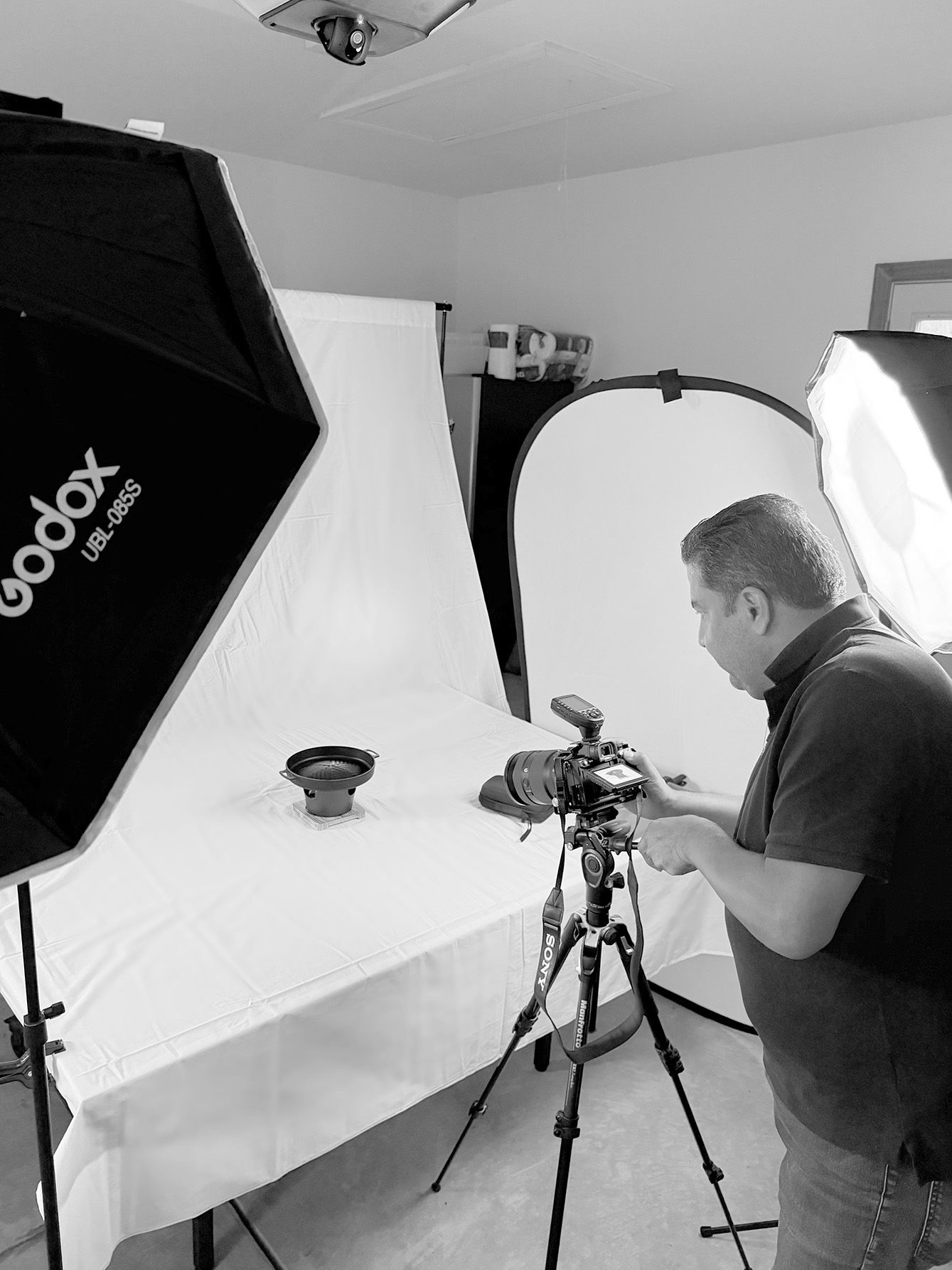 Professional photographer in a studio setting taking a product photo with a lighting setup.