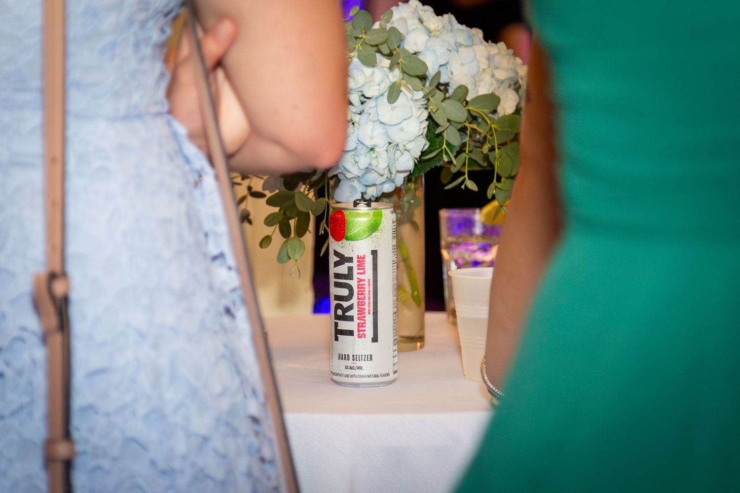 Close-up of a signature drink centered on a table between two chatting guests.