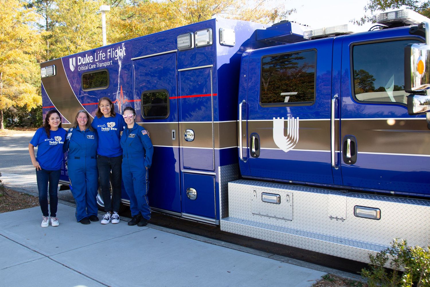 Group portrait of the Duke University air ambulance crew standing beside their medical helicopter.