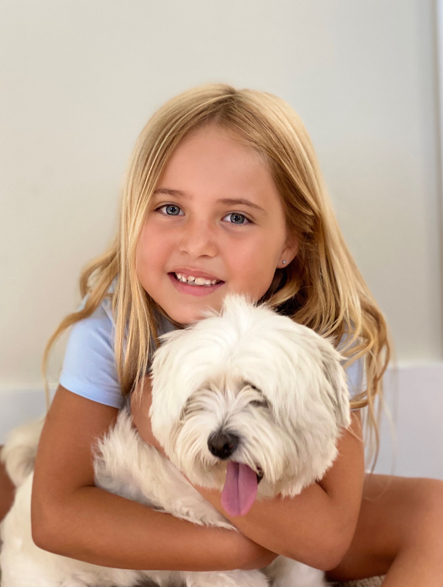 Little girl holding her dog during a warm outdoor moment — sweet lifestyle photography.