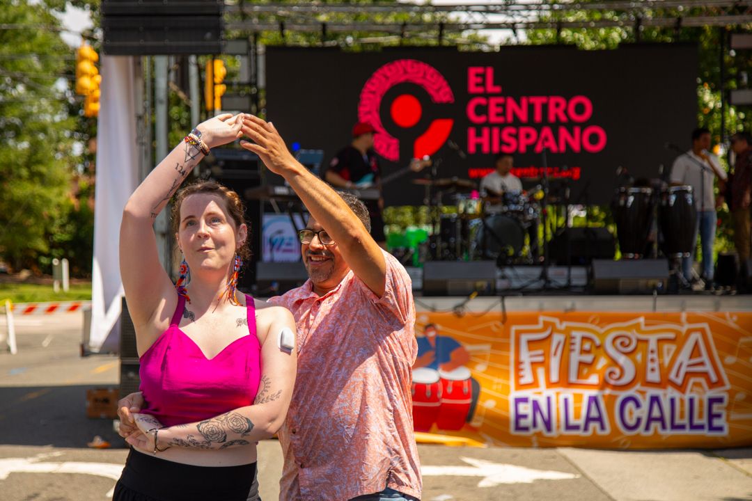 Celebración cultural con pareja bailando música latina en el festival del Centro Hispano