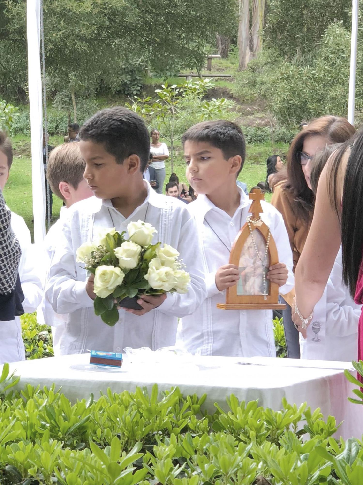 Two children respectfully presenting the gifts during the offertory at their First Communion mass.