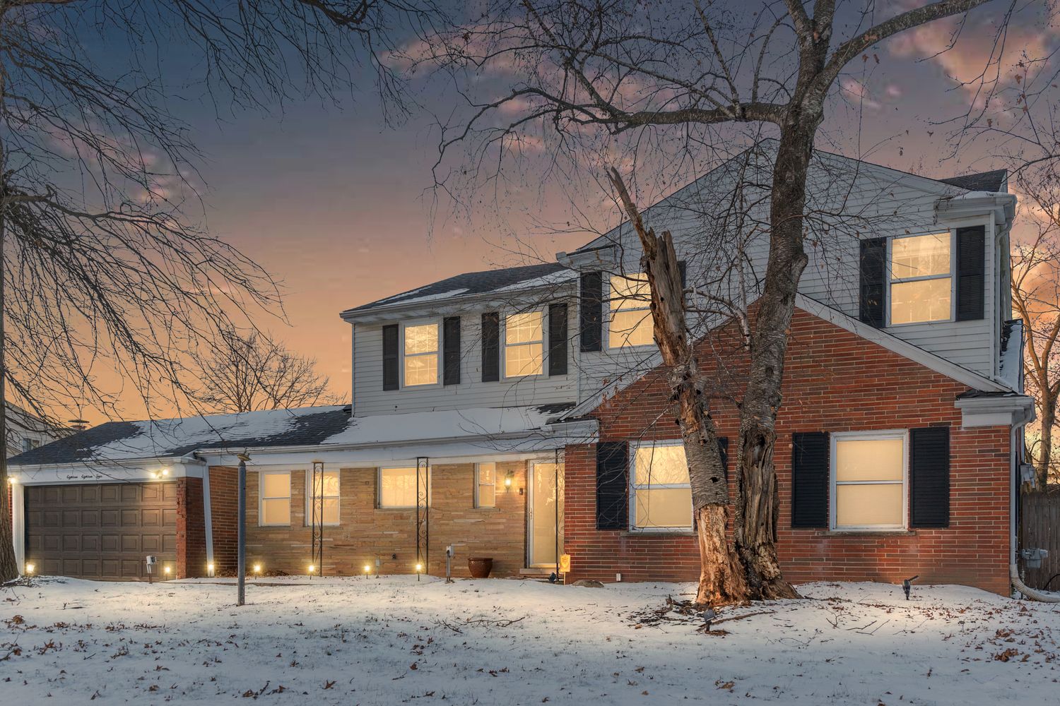 Snowy winter view of residential homes at dusk with warm window lighting creating a cozy atmosphere.