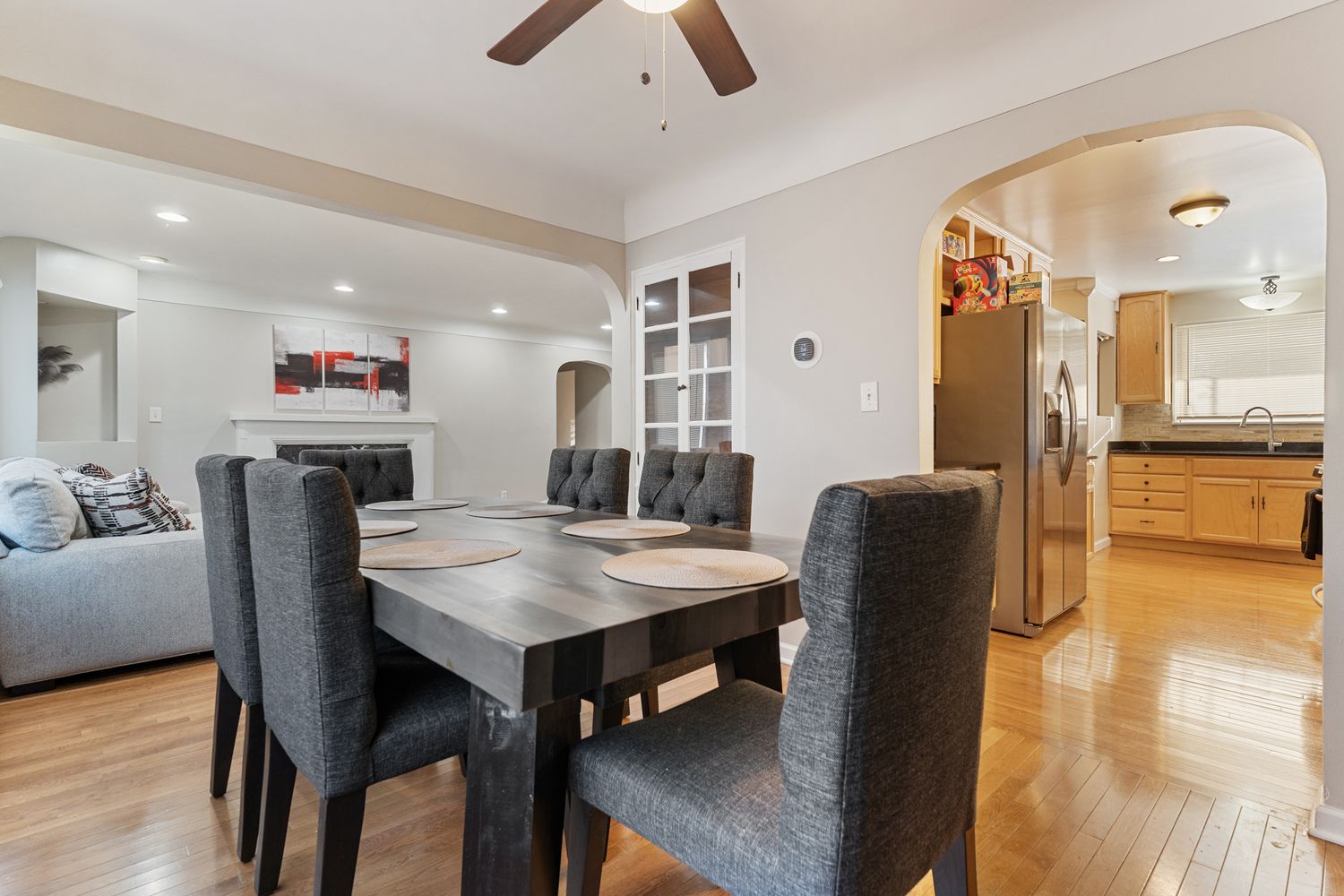 Modern open concept kitchen and living area with hardwood floors and recessed lighting.