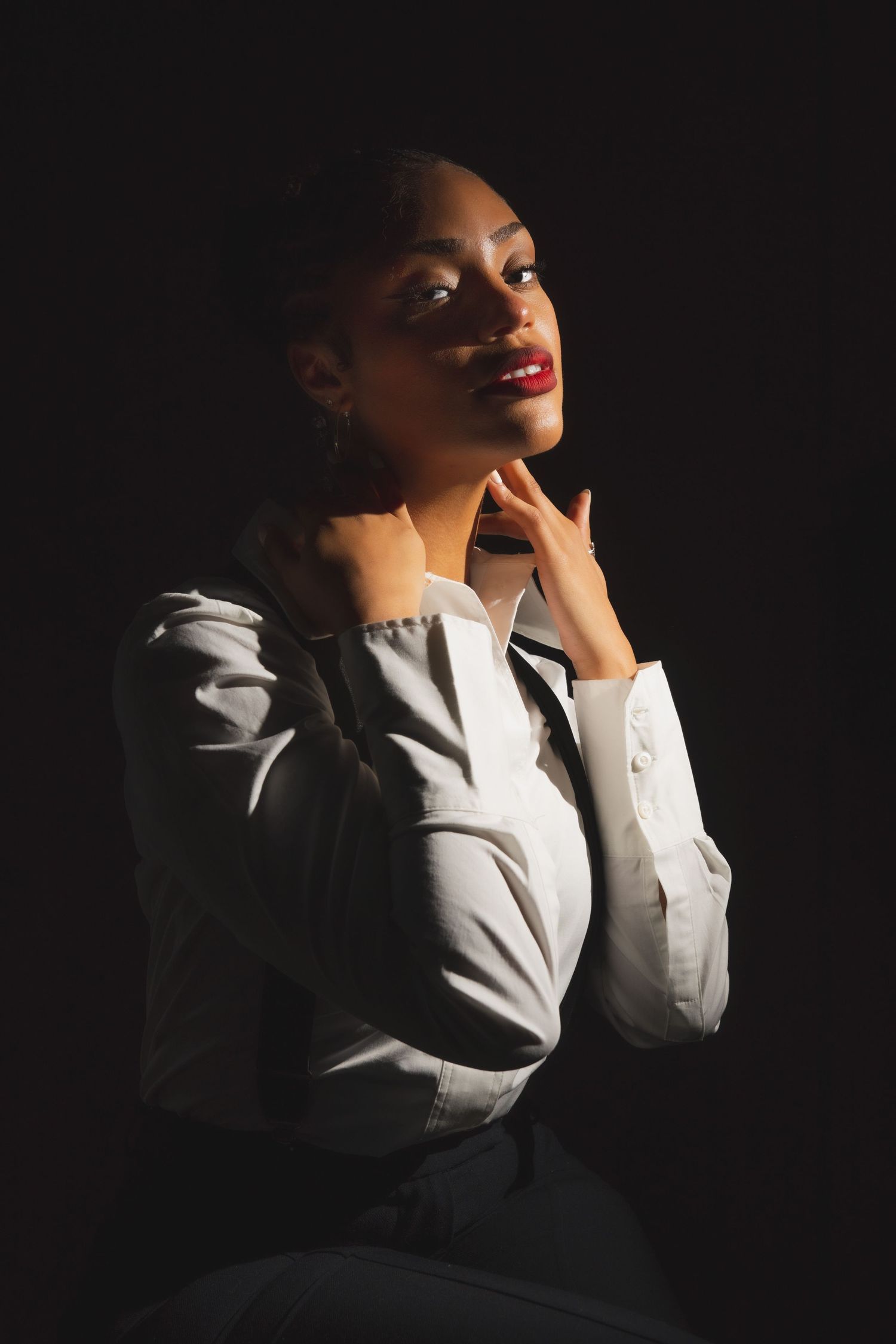 A dramatic portrait series against dark background showing elegant poses in professional attire.