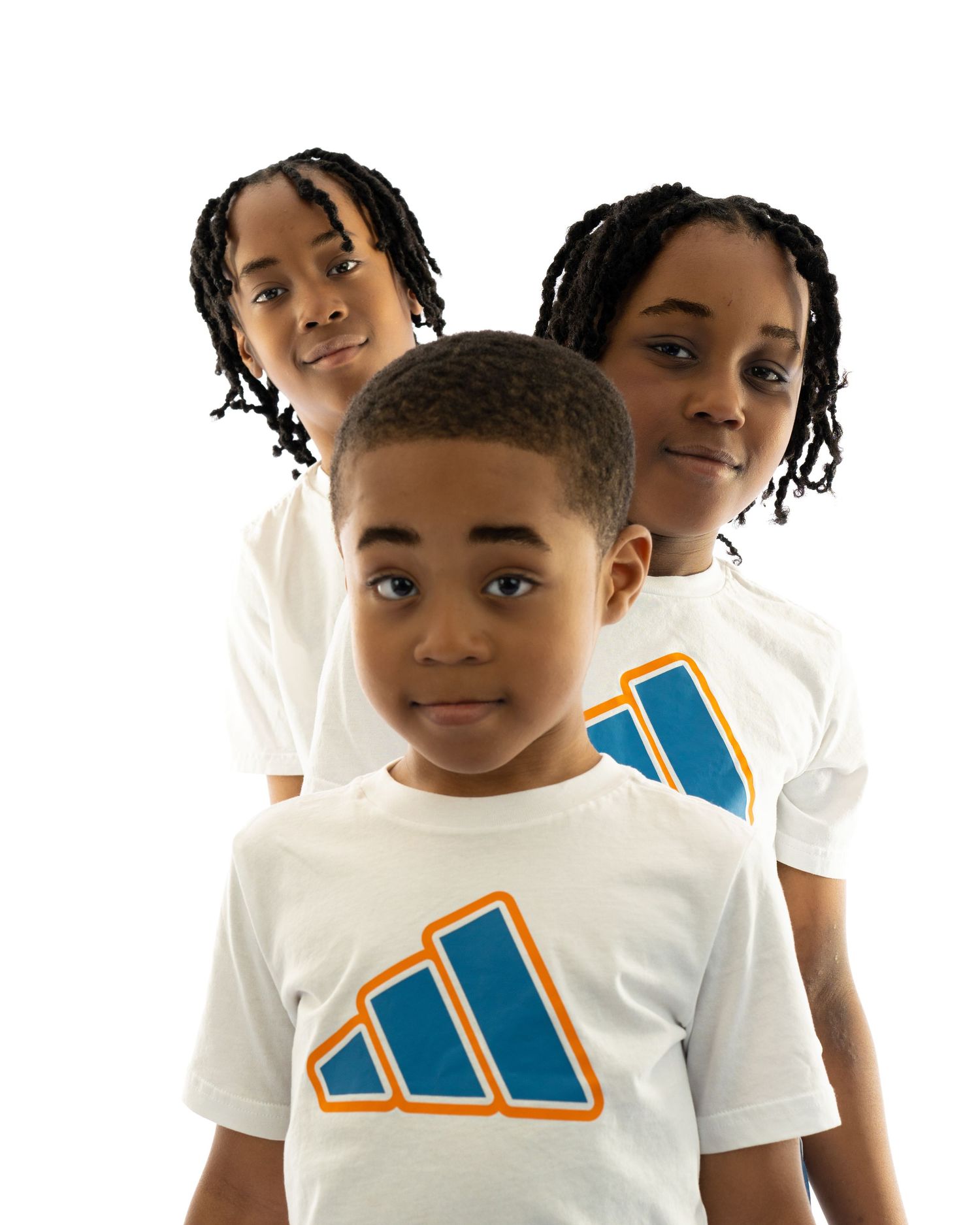 Three children wearing matching white Adidas logo t-shirts pose together against a white background.