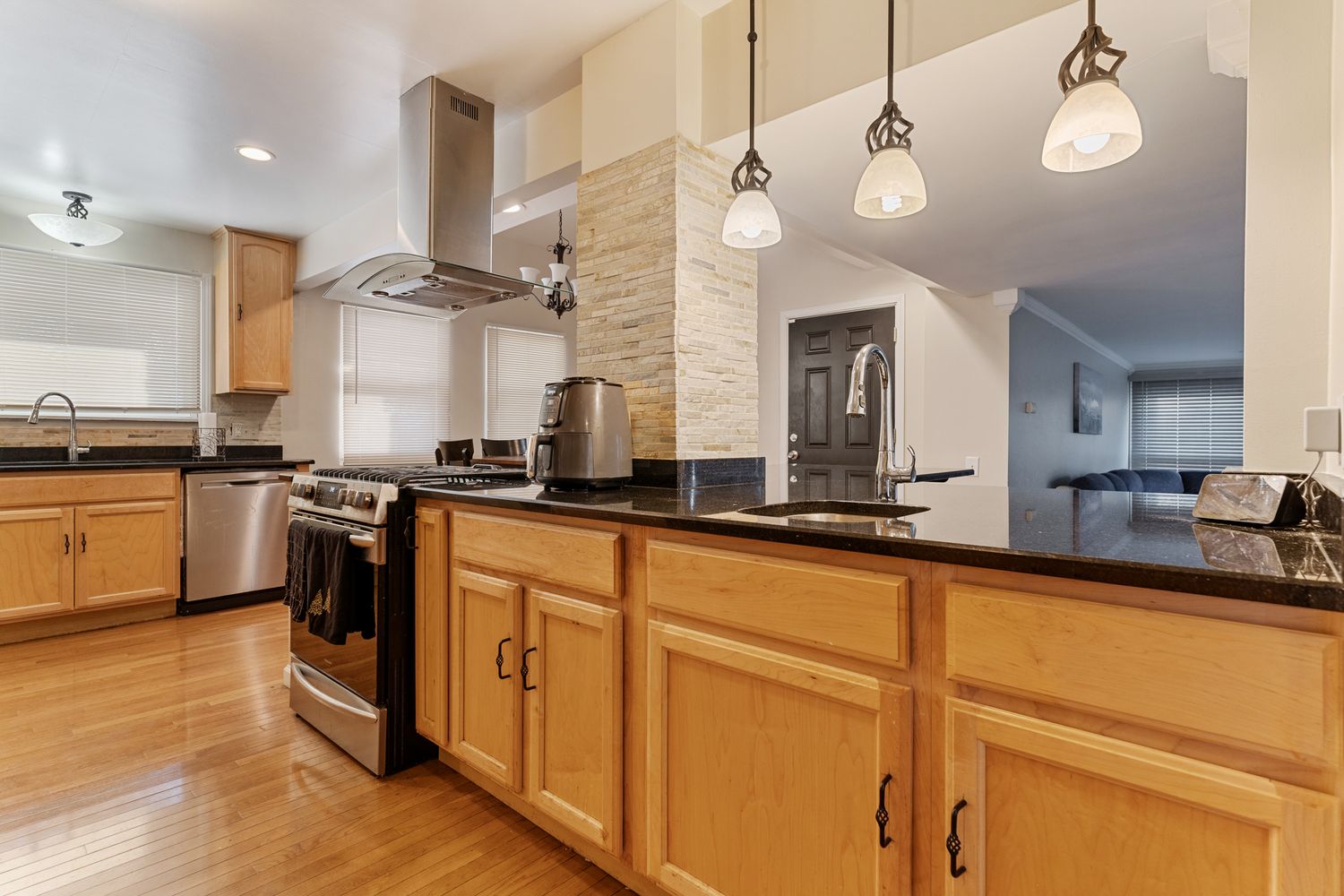 Bright kitchen with wooden cabinets, pendant lights, and stainless steel appliances.