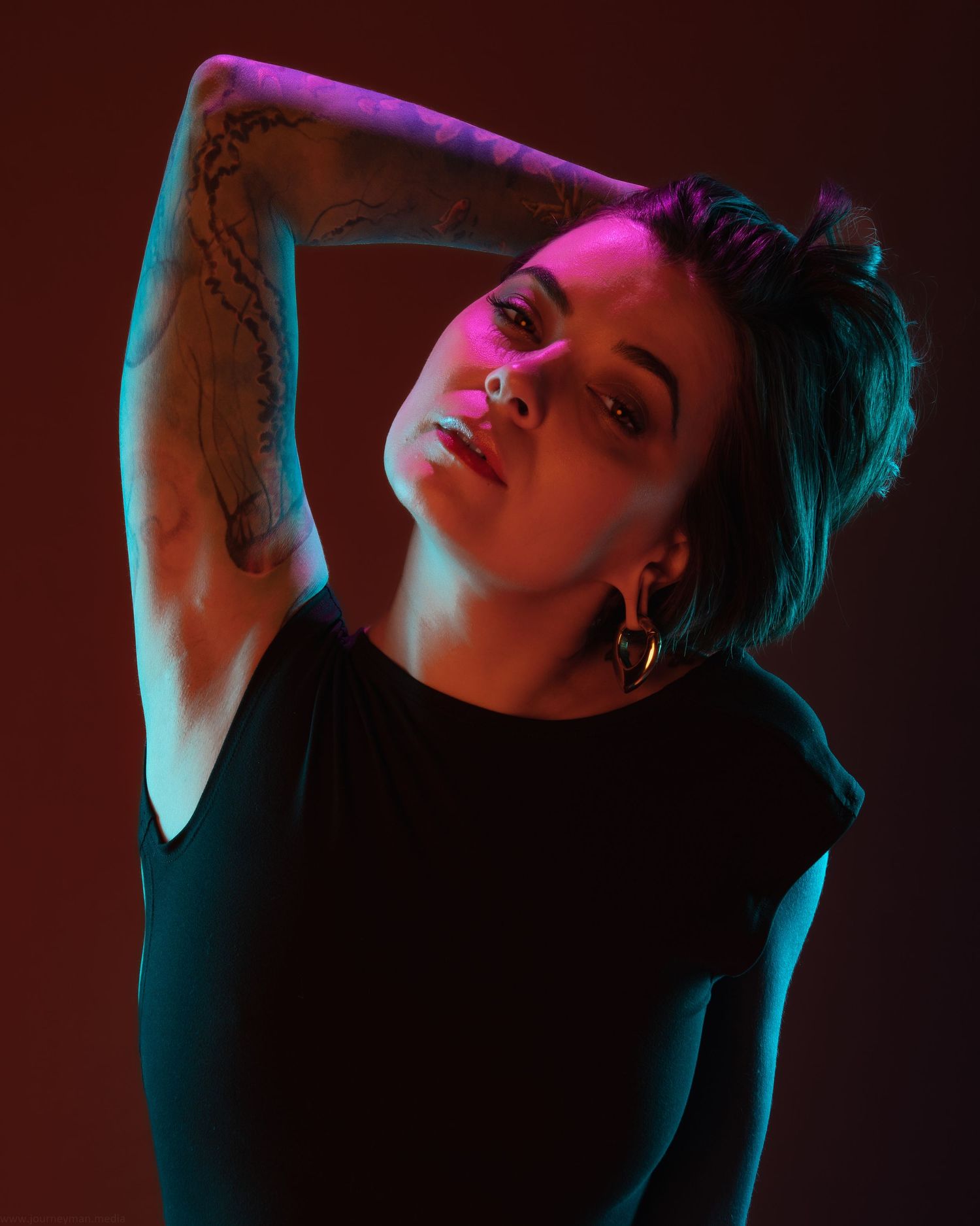 Artistic portrait with neon pink and blue lighting creating a moody atmosphere.