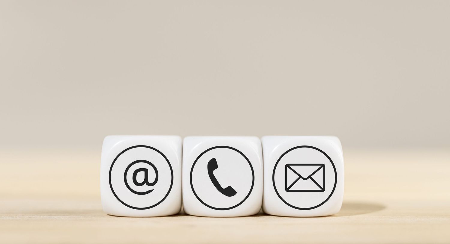Minimalist white dice showing communication icons against beige background.