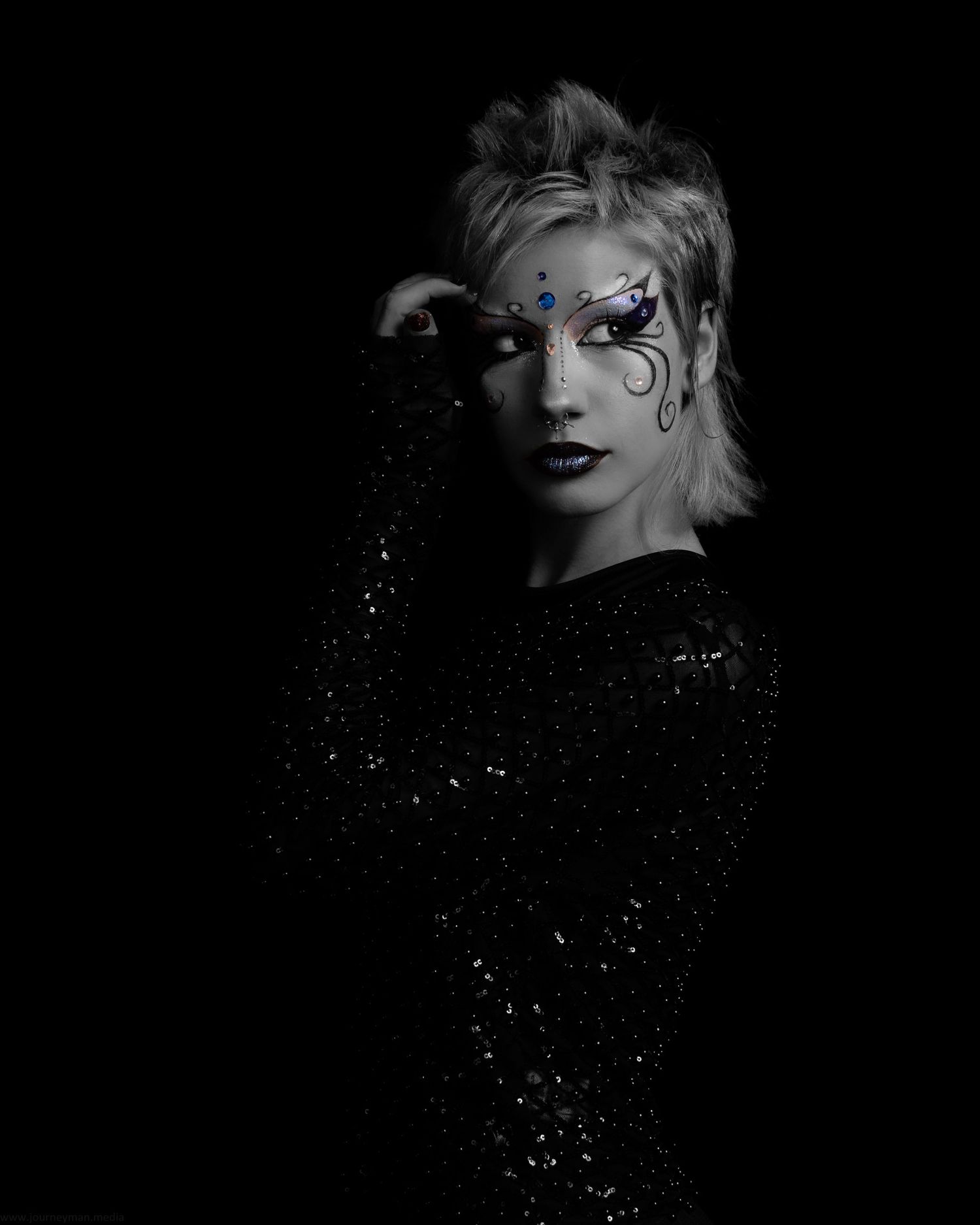 Dramatic black and white portrait with glittery makeup and dark shadows.