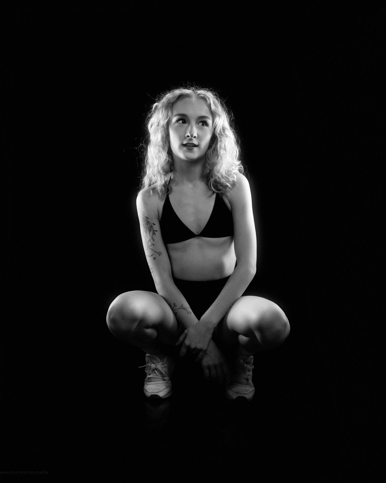 A dramatic black and white photo series showing a figure in dark clothing crouched in different poses against a black background.