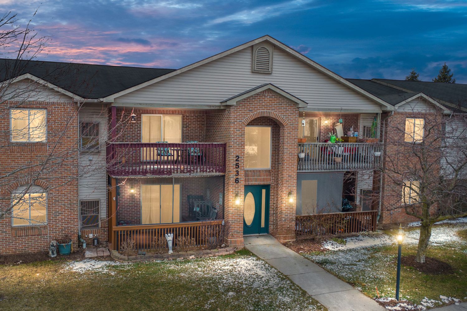 Exterior view of modern residential homes with brick facades at dusk showing warm lighting and architectural details.