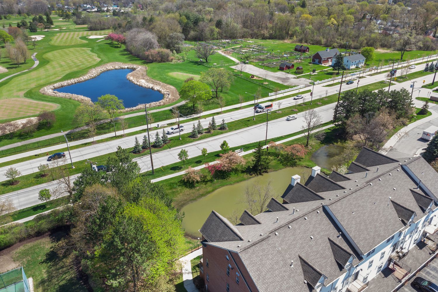 Aerial view of residential neighborhood with landscaped yards, walking paths and a small pond.