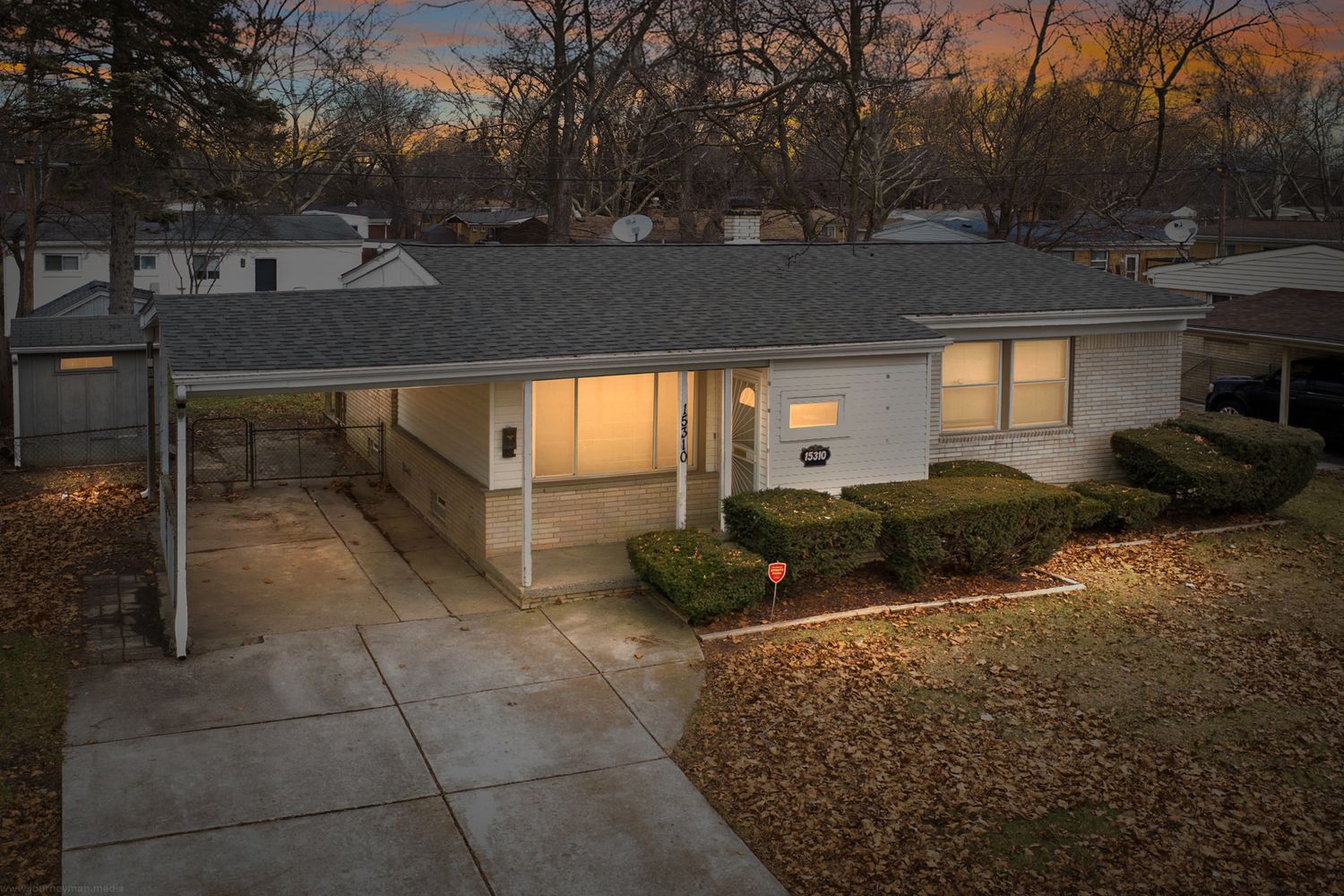 Exterior view of residential homes at dusk with dramatic orange sky and fall foliage.