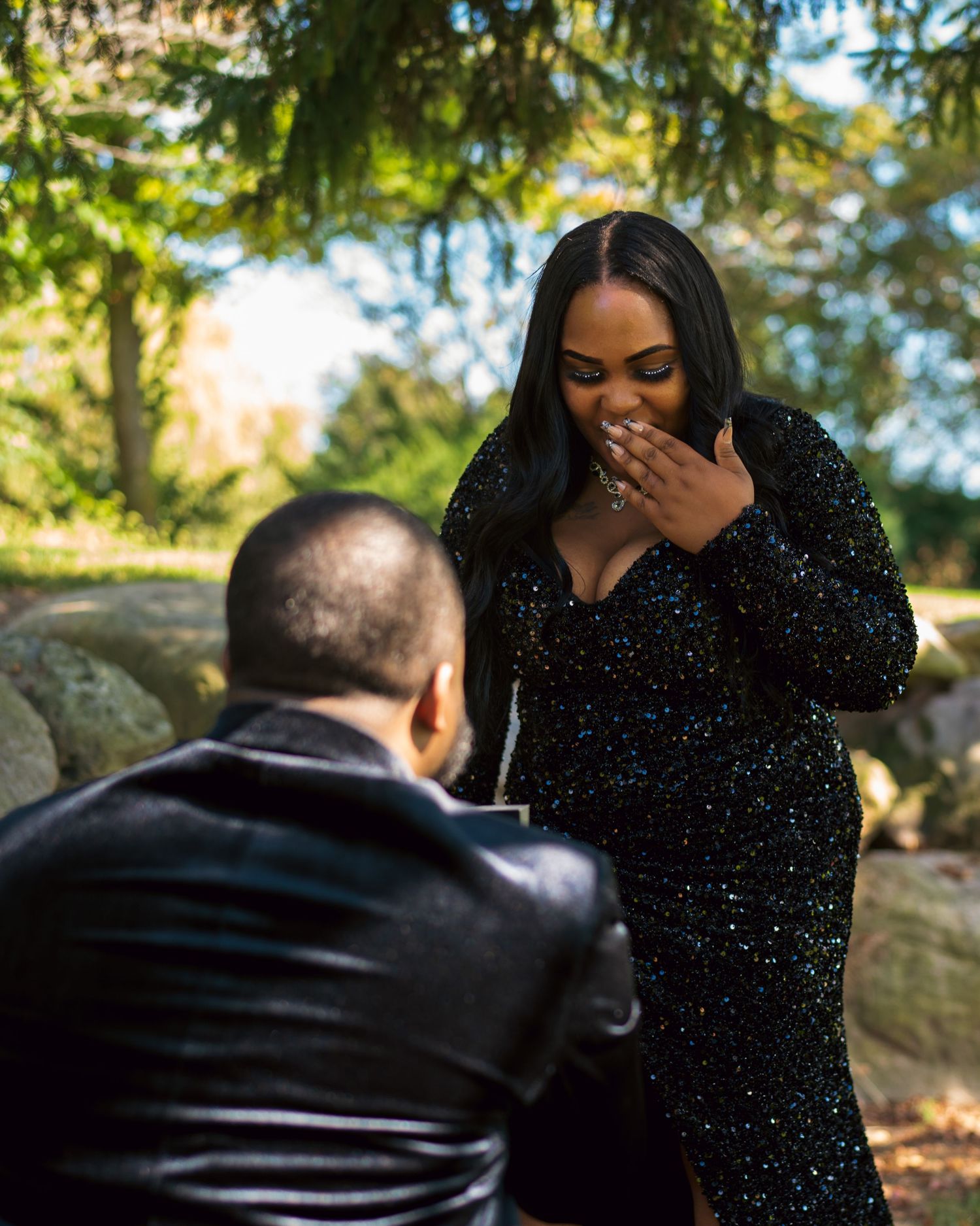 A couple sharing a joyful moment outdoors in an autumn setting with natural sunlight filtering through trees.