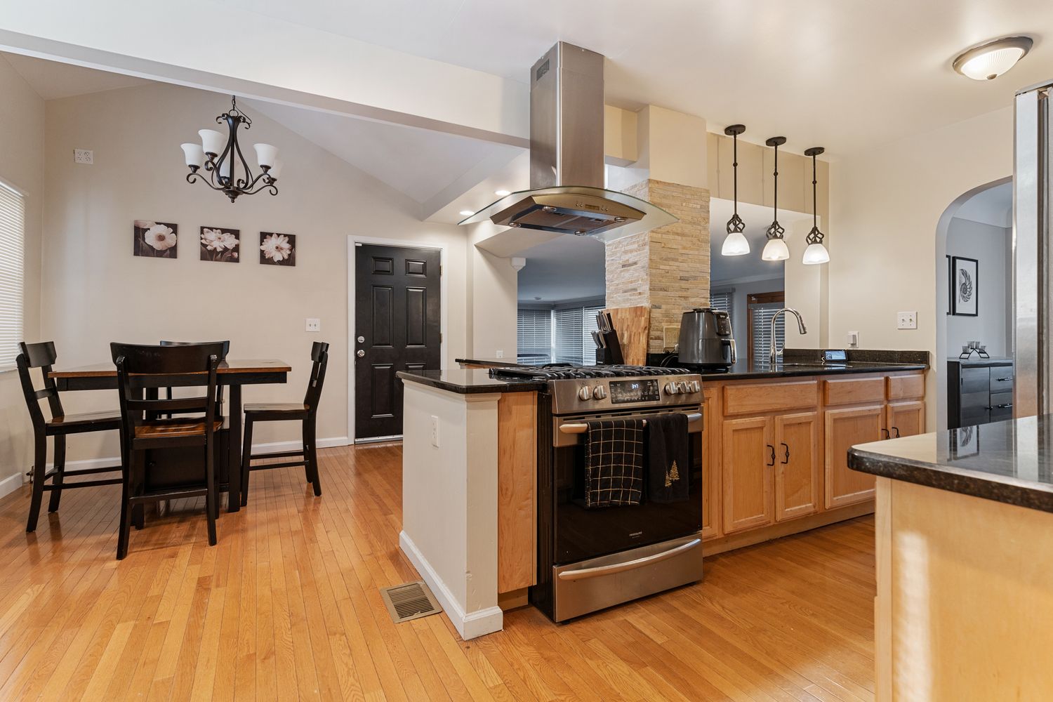 Open concept dining and kitchen area with hardwood floors and pendant lighting fixtures.