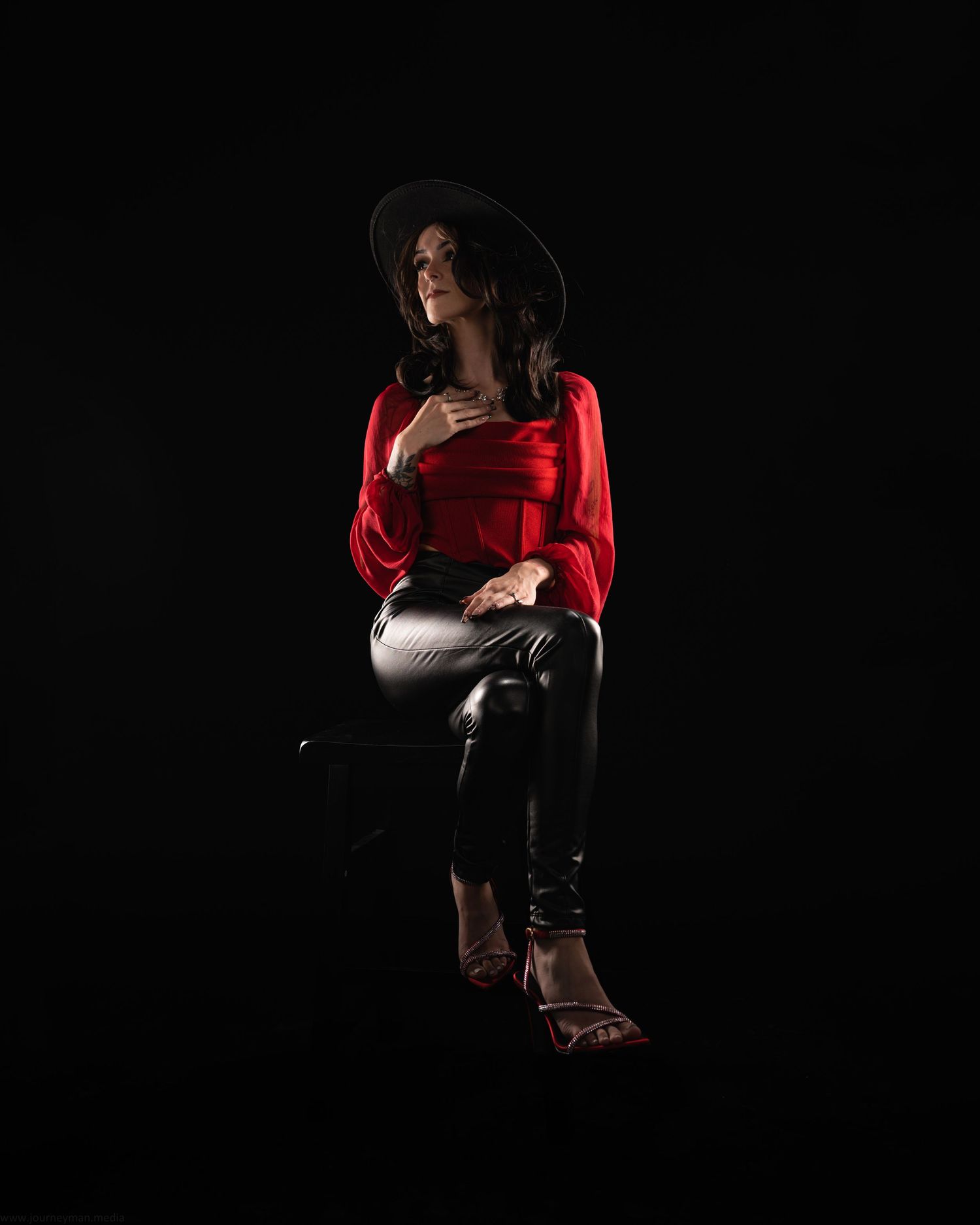 Artistic low-key portrait series with figure seated in shadows wearing red top.
