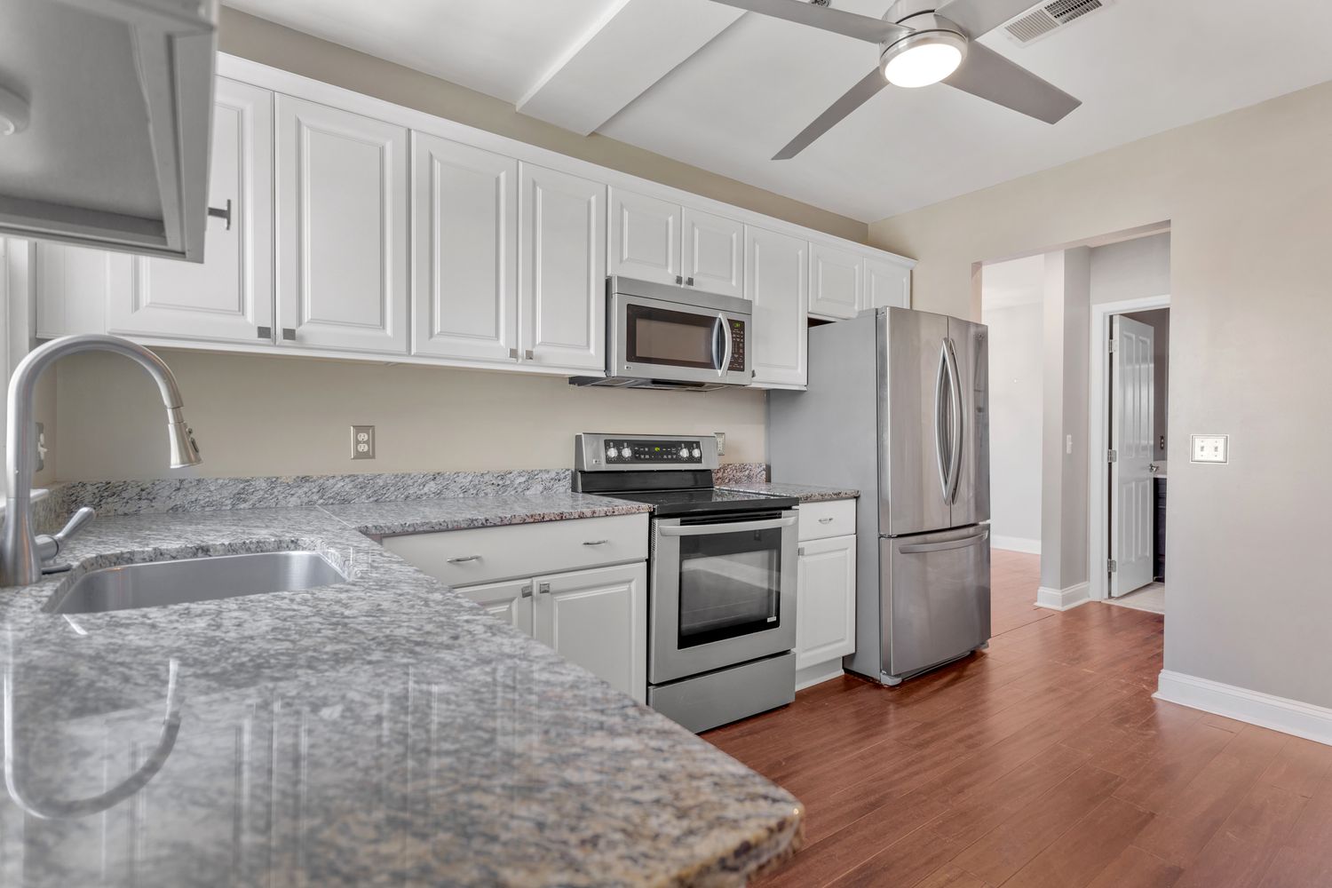 Contemporary kitchen with stainless steel appliances, granite countertops and white cabinetry.