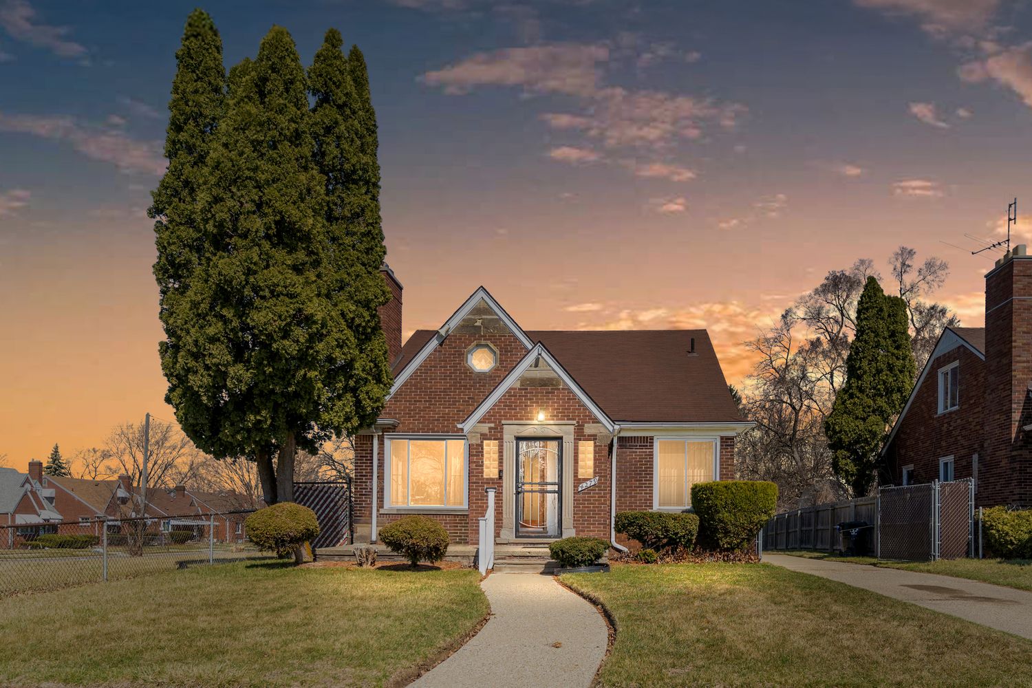 Panoramic view of suburban neighborhood houses at sunset with blue sky and trees.