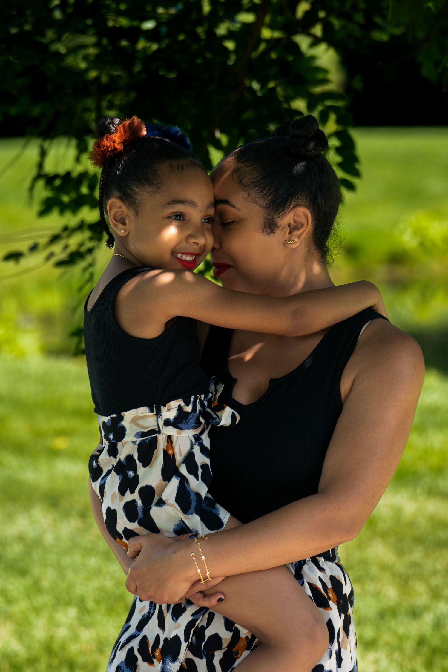 A tender embrace shared on a sunny day in a lush green park setting.