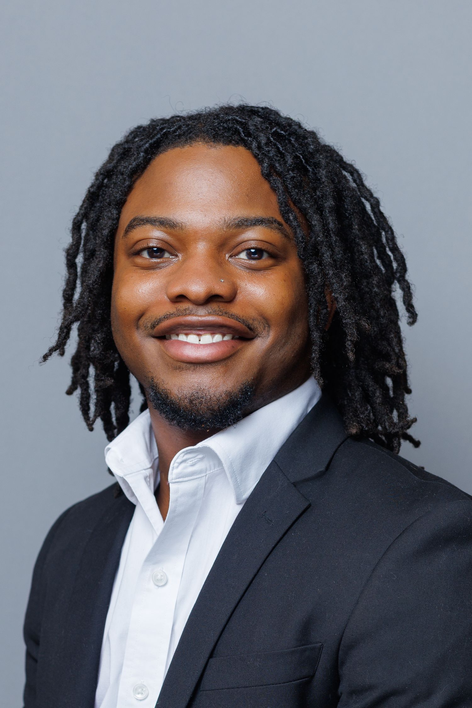 Headshot image of young male in white dress shirt and dark suit jacket