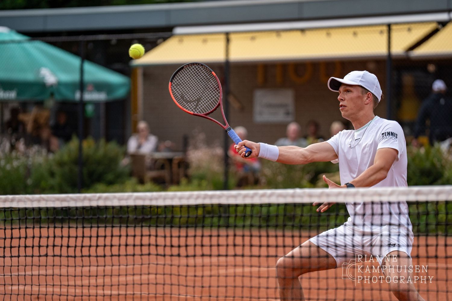 Actiefoto's van gravel tennistoernooi met spelers in actie, dubbelspel, toeschouwers en zomerse sfeer rond de baan.