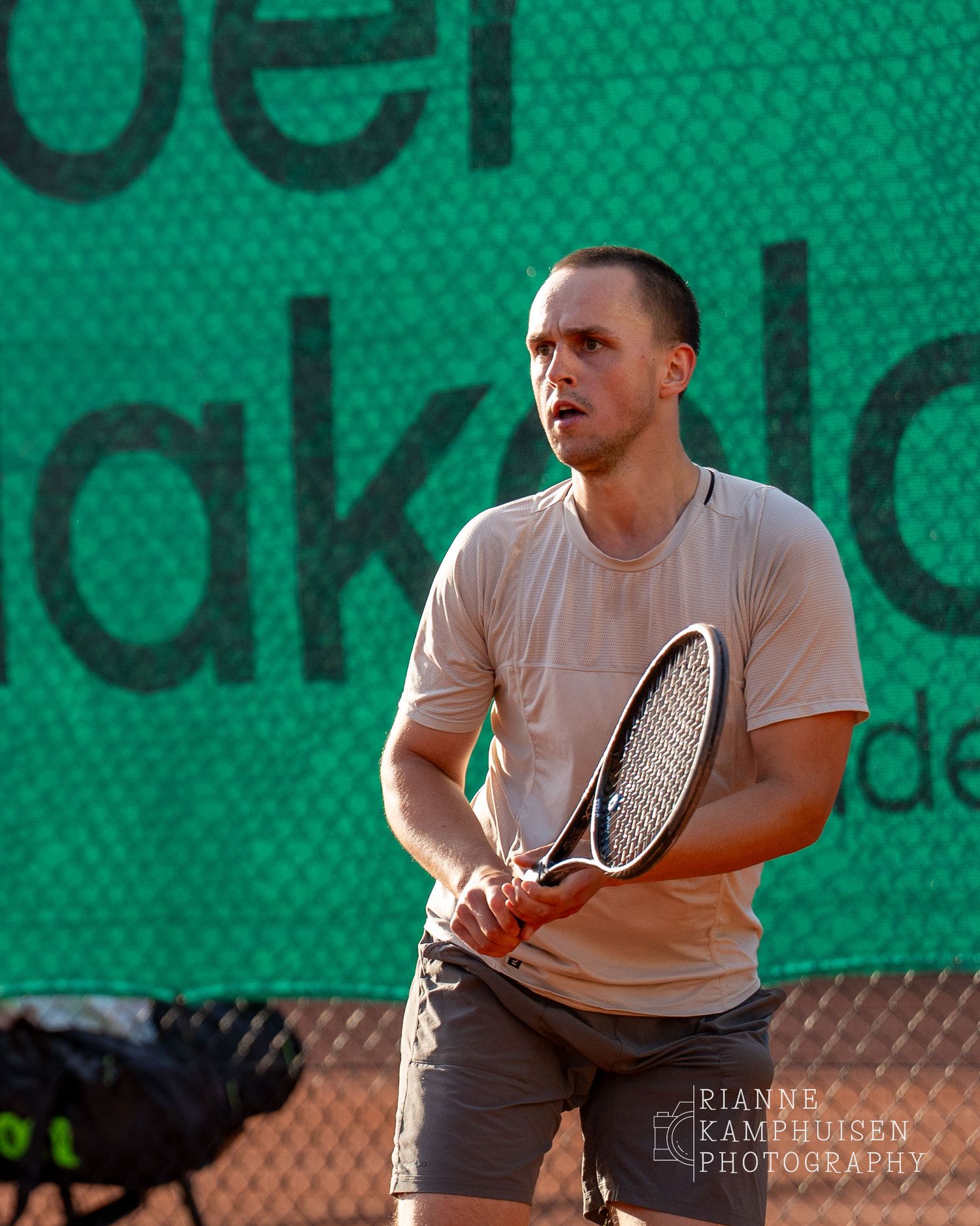 Actiefoto's van de vrijdagavond van een gravel tennistoernooi met spelers in actie, dubbelspel, toeschouwers en zomerse sfeer rond de baan.