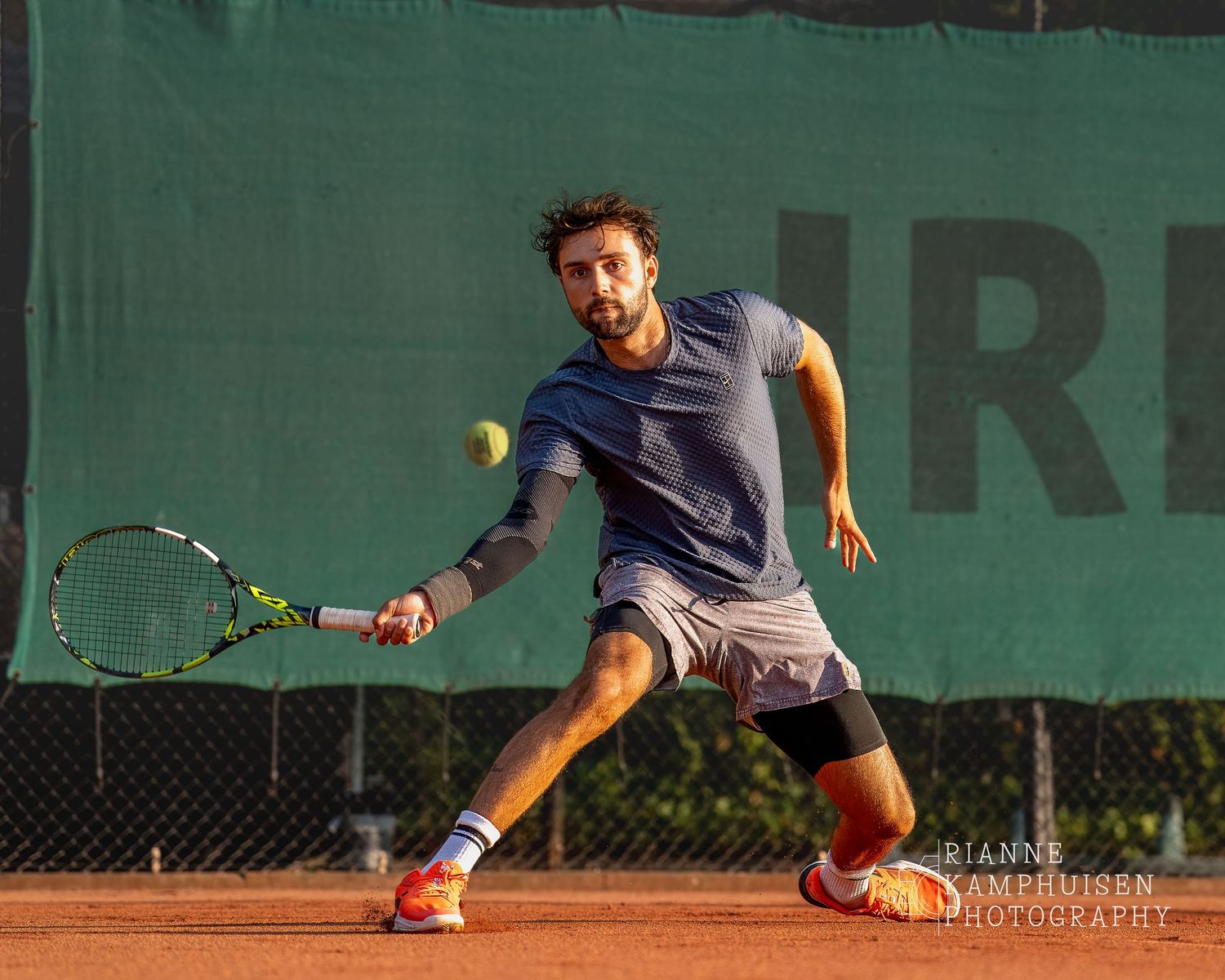 Actiefoto's van de woensdagavond van eengravel tennistoernooi met spelers in actie, dubbelspel, toeschouwers en zomerse sfeer rond de baan.v