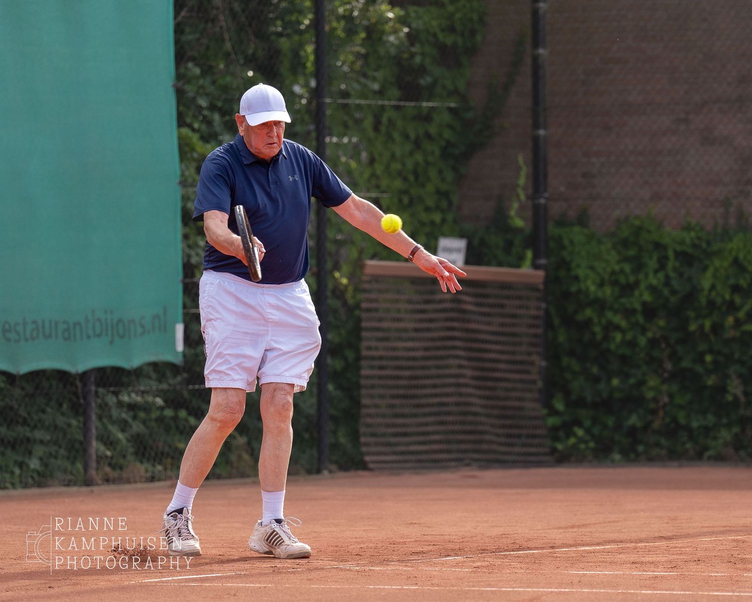 Actiefoto's van gravel tennistoernooi met spelers in actie, dubbelspel, toeschouwers en zomerse sfeer rond de baan.
