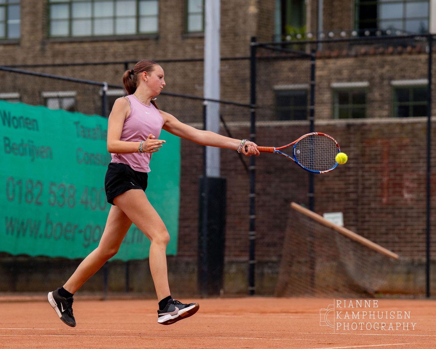 Actiefoto's van de vrijdagavond van een gravel tennistoernooi met spelers in actie, dubbelspel, toeschouwers en zomerse sfeer rond de baan.