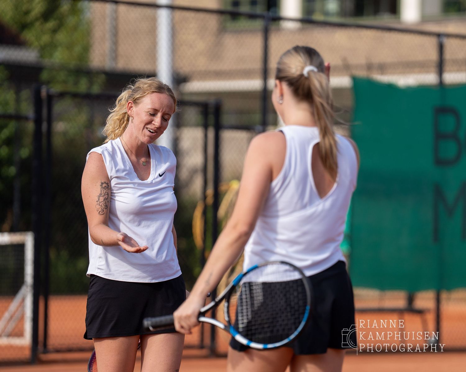 Actiefoto's van gravel tennistoernooi met spelers in actie, dubbelspel, toeschouwers en zomerse sfeer rond de baan.