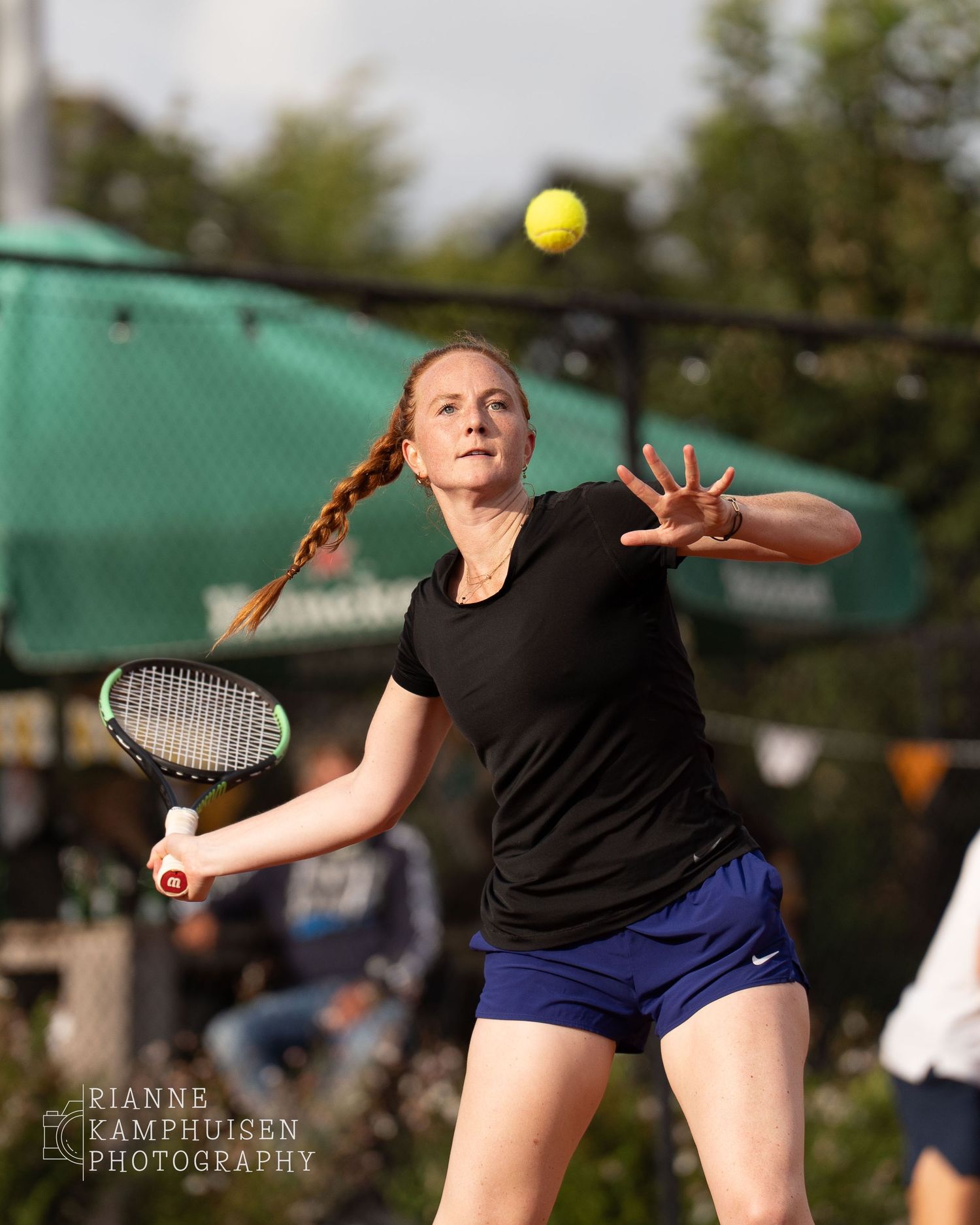 Actiefoto's van de vrijdagavond van een gravel tennistoernooi met spelers in actie, dubbelspel, toeschouwers en zomerse sfeer rond de baan.
