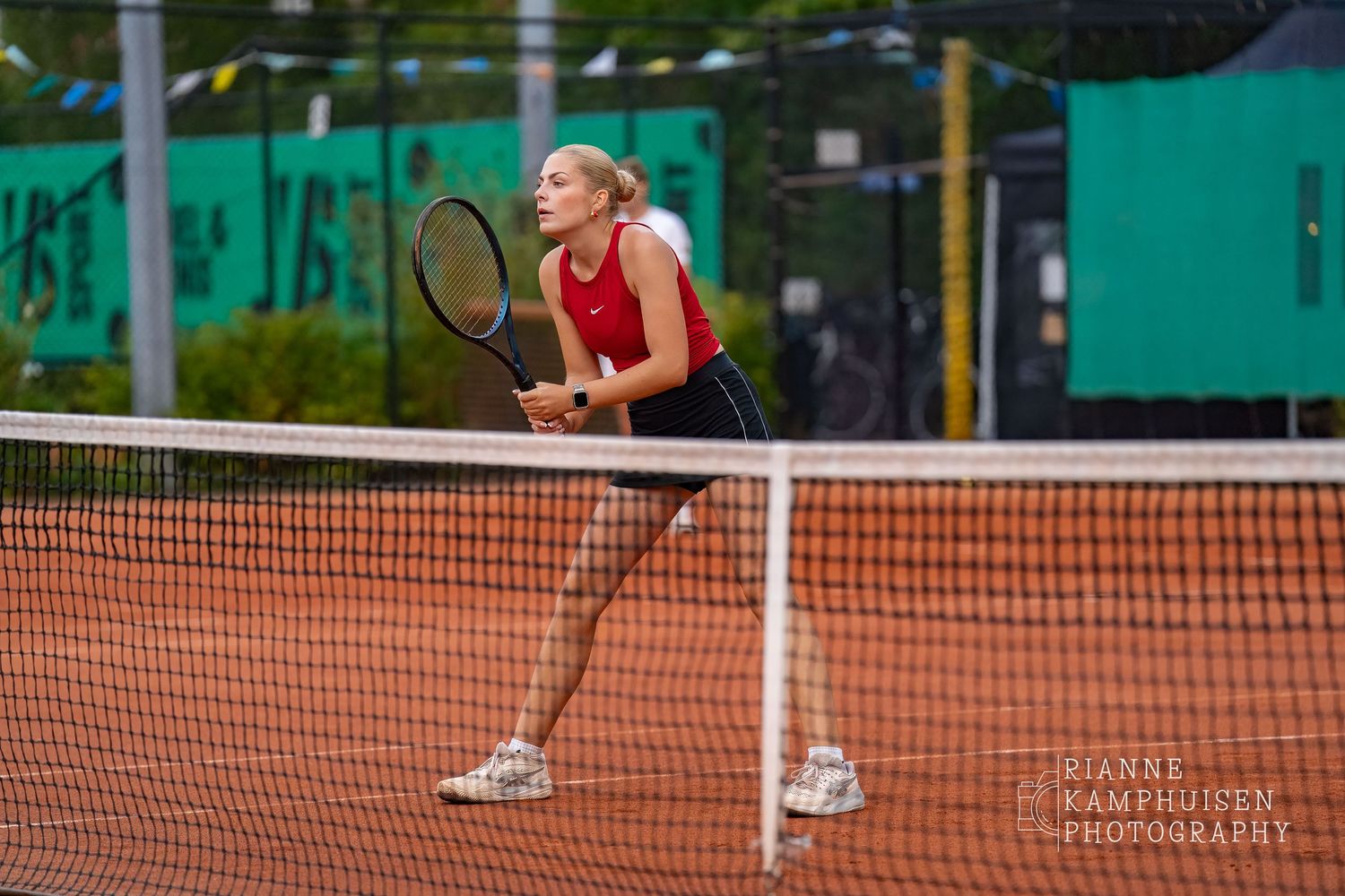 Actiefoto's van de woensdagavond van eengravel tennistoernooi met spelers in actie, dubbelspel, toeschouwers en zomerse sfeer rond de baan.