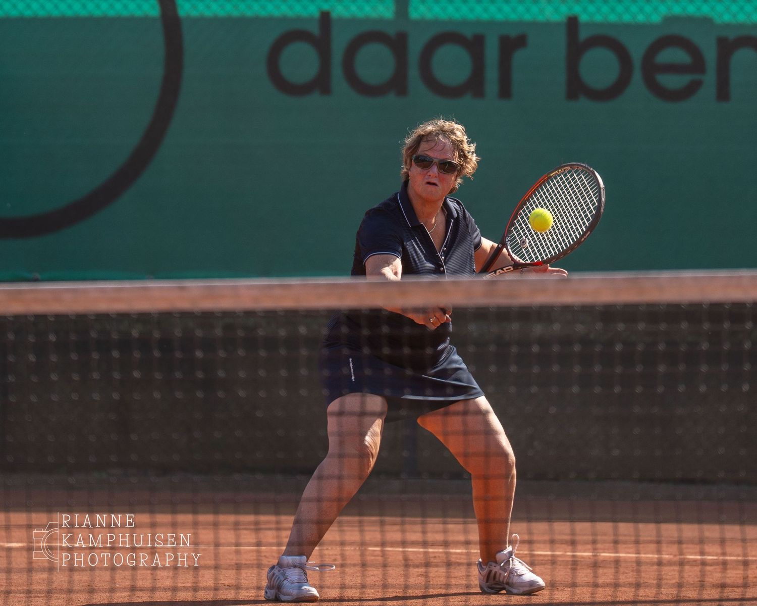 Actiefoto's en finalisten van een gravel tennistoernooi met spelers in actie, dubbelspel, toeschouwers en zomerse sfeer rond de baan.