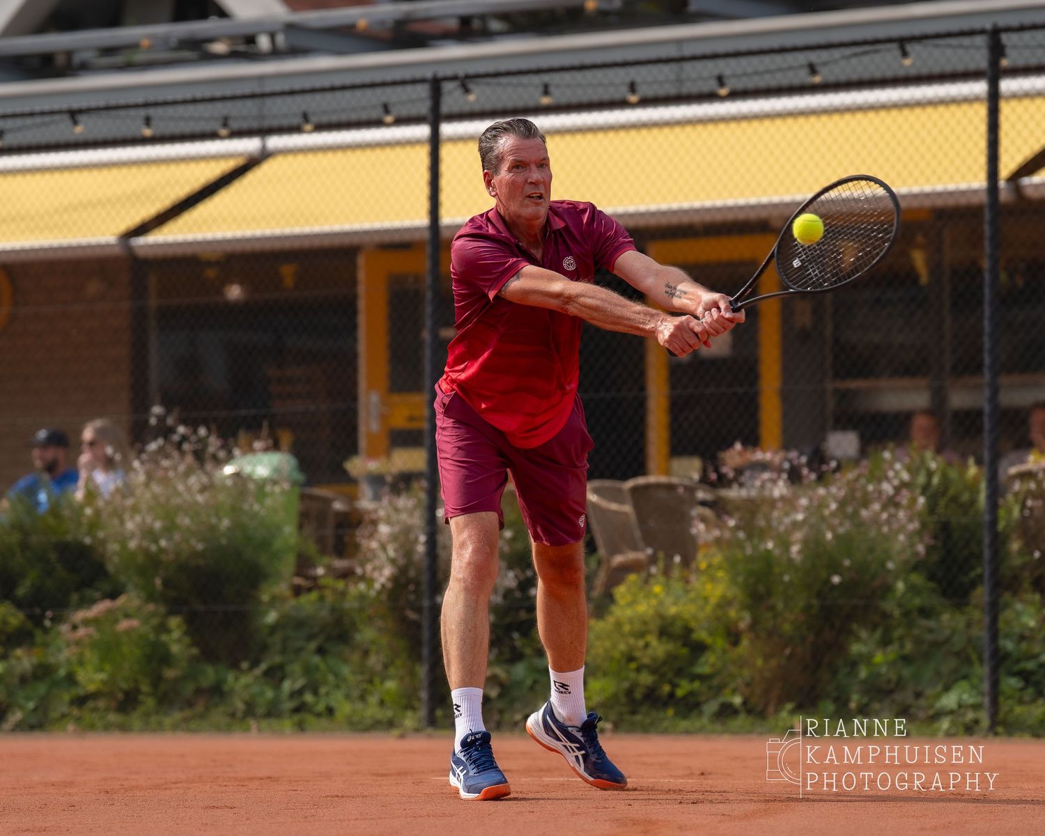 Actiefoto's van de vrijdagavond van een gravel tennistoernooi met spelers in actie, dubbelspel, toeschouwers en zomerse sfeer rond de baan.